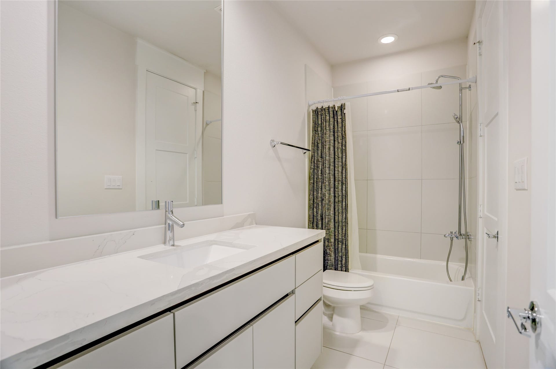 9820 Mocking Bird Hill Lane, Houston, TX 77080 Sleek modern bathroom with a spacious vanity, elegant white countertop, and a combination shower and bathtub.