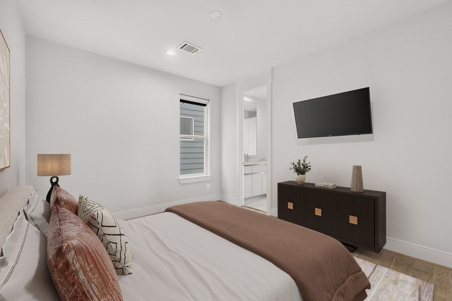 9820 Mocking Bird Hill Lane, Houston, TX 77080 a second cozy guest bedroom with a neutral palette, featuring a comfortable bed, modern dresser, wall-mounted TV, and access to the shared en-suite bathroom.