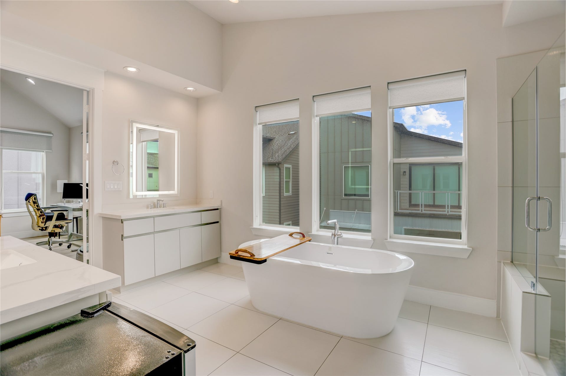 9820 Mocking Bird Hill Lane, Houston, TX 77080 Spacious, modern bathroom features a luxurious freestanding tub, large windows for natural light, and sleek vanities, creating a serene retreat.