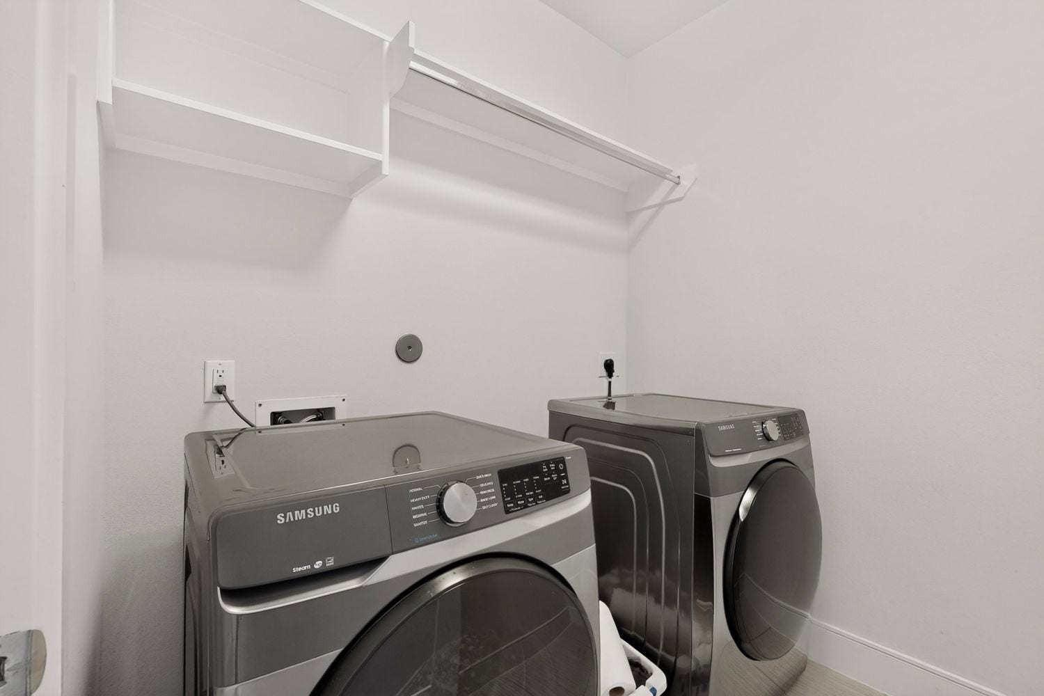9820 Mocking Bird Hill Lane, Houston, TX 77080 Modern laundry room featuring sleek Samsung washer and dryer, complemented by ample shelving for storage.