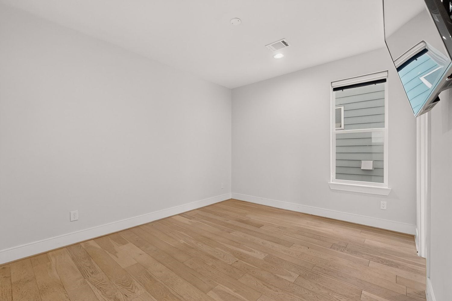 9820 Mocking Bird Hill Lane, Houston, TX 77080 a vacant look at the bright and airy 2nd guest room featuring sleek hardwood floors, clean white walls, and a modern recessed lighting fixture, perfect for customization.