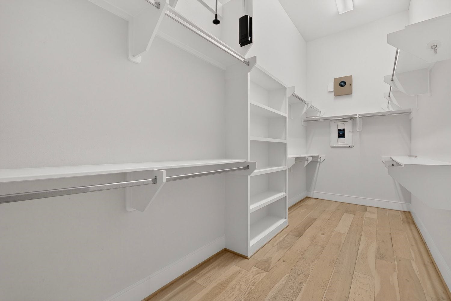 9820 Mocking Bird Hill Lane, Houston, TX 77080 Spacious walk-in closet with ample shelving and hanging space, featuring sleek white finishes and light hardwood floors for a modern touch.