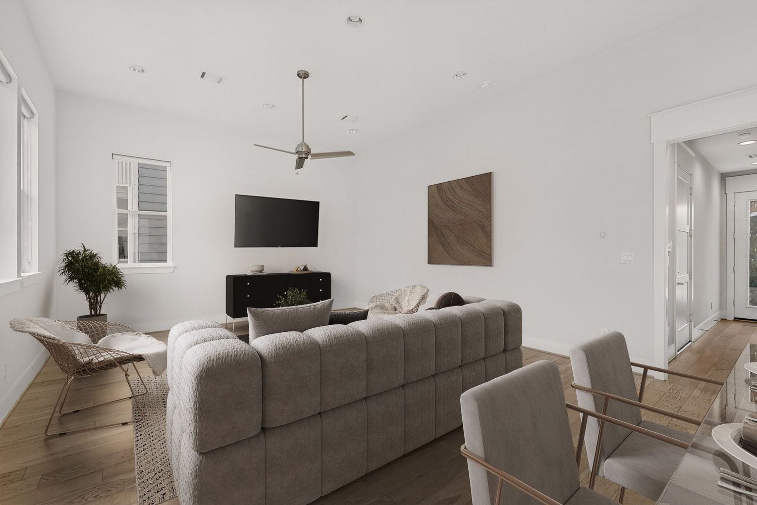 9820 Mocking Bird Hill Lane, Houston, TX 77080 Spacious and modern living room featuring an area fora sectional sofa, sleek ceiling fan, mounted TV, and abundant natural light from large windows.