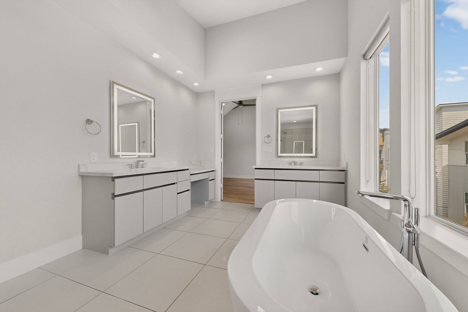 9820 Mocking Bird Hill Lane, Houston, TX 77080 Spacious and modern bathroom featuring dual vanities, sleek cabinetry, and a luxurious freestanding tub set against awesome windows for abundant natural light.