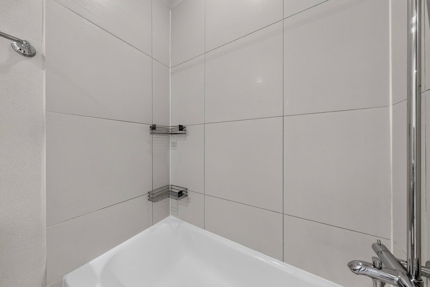9820 Mocking Bird Hill Lane, Houston, TX 77080 The Sleek and modern shared guest bathroom with large tiles, a chrome showerhead, and convenient corner shelving for storage.