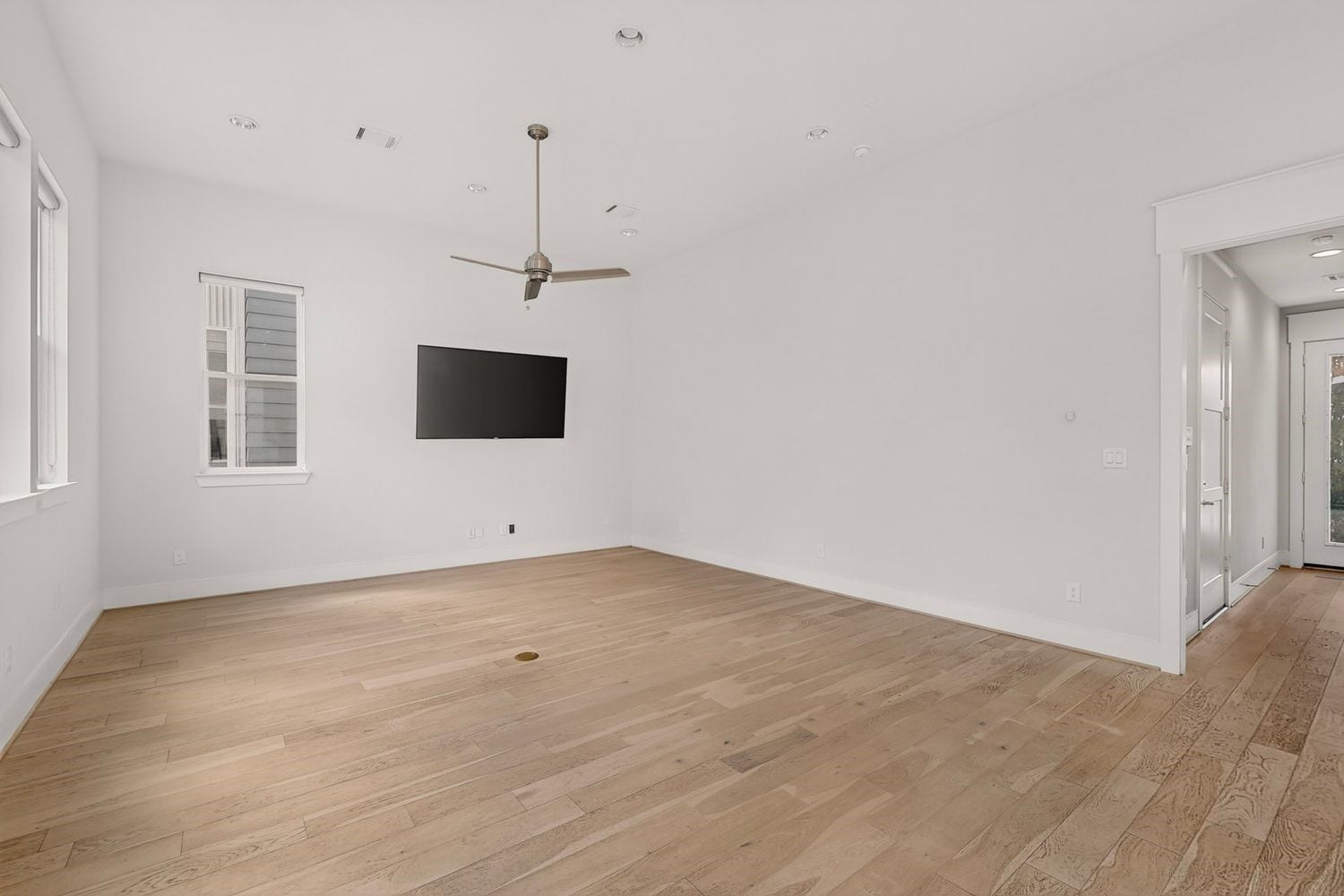 9820 Mocking Bird Hill Lane, Houston, TX 77080 The vacant look at the Spacious living area with elegant hardwood floors, a modern ceiling fan, and a mounted TV, offering ample natural light through multiple windows.