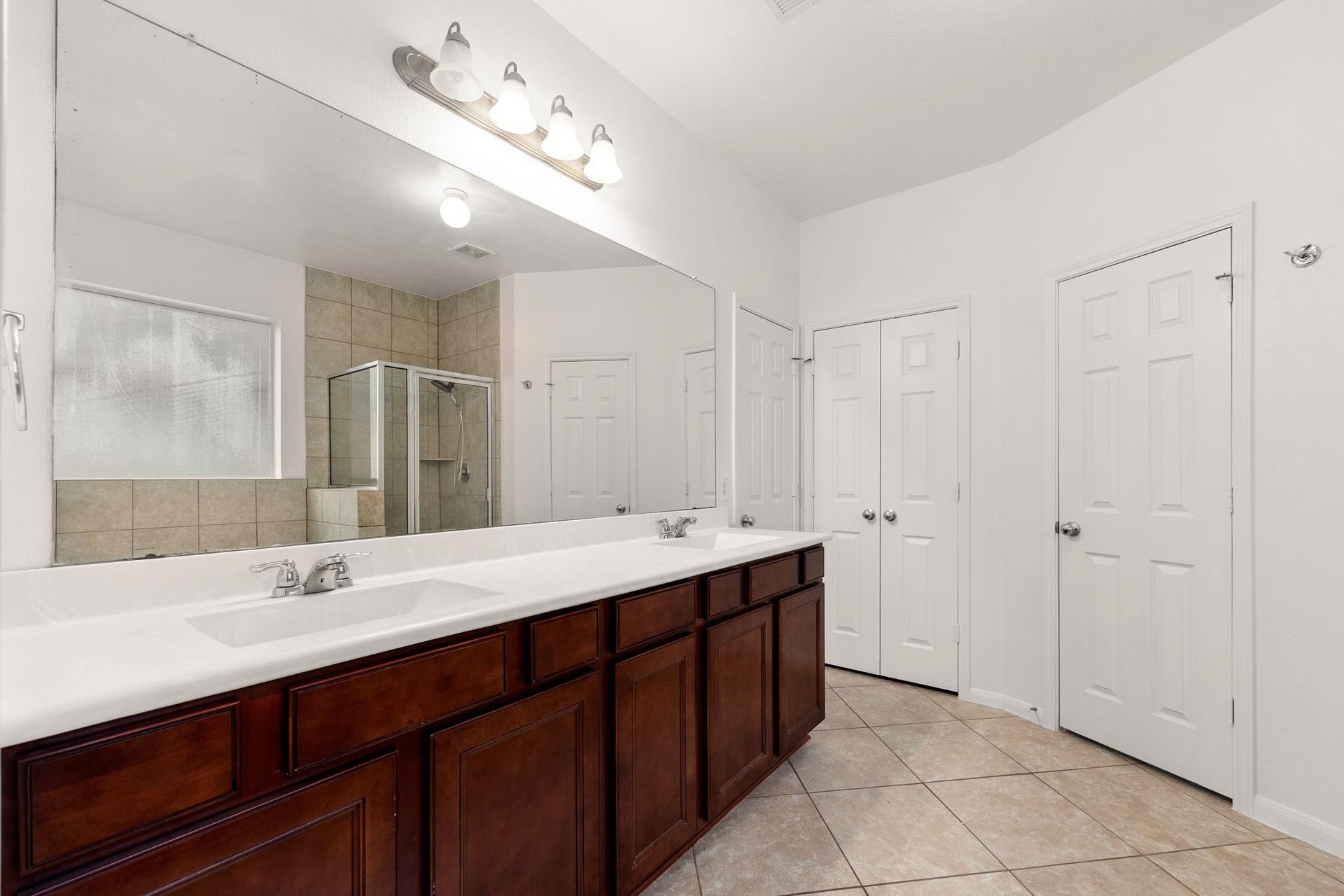 26311 Smokey Valley Lane, Katy, TX 77494 The ensuite bath pairs rich cherry-tone cabinetry with dual sinks and an expansive vanity mirror, plus a linen closet for extra storage.