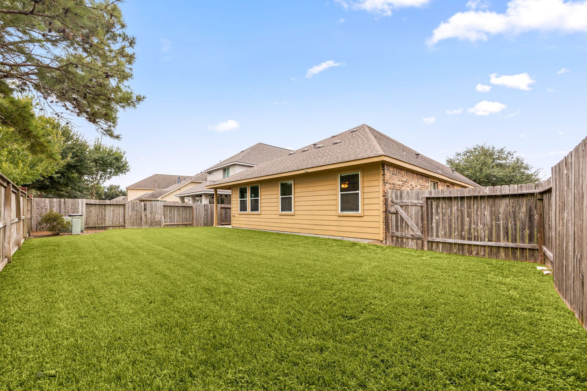 26311 Smokey Valley Lane, Katy, TX 77494 The spacious backyard wraps alongside the home, with privacy fencing, a side gate, and mature trees framing the view.