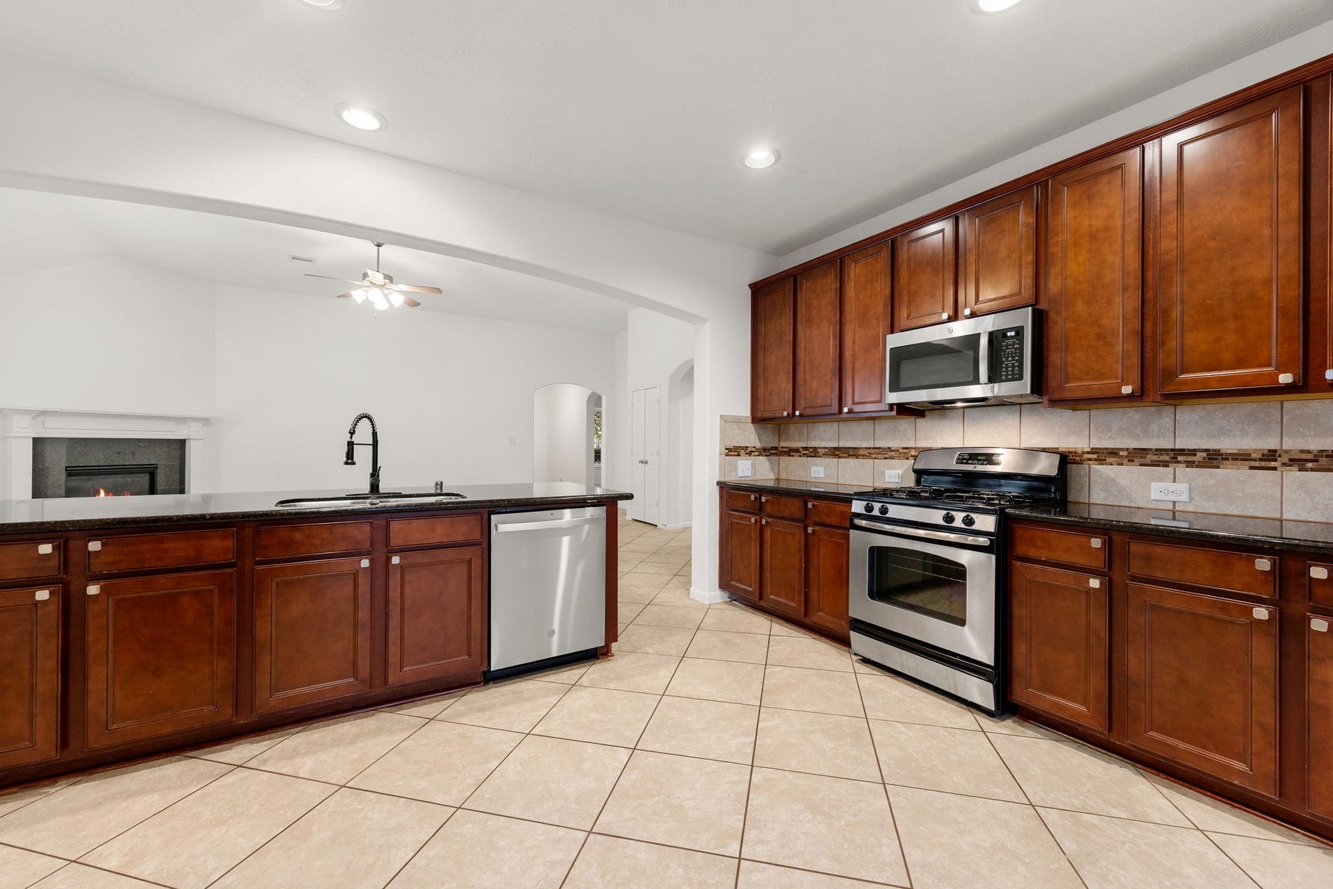 26311 Smokey Valley Lane, Katy, TX 77494 A gas range and built-in microwave are surrounded by gleaming granite countertops, abundant cabinetry, and a tile backsplash accented with a mosaic band.