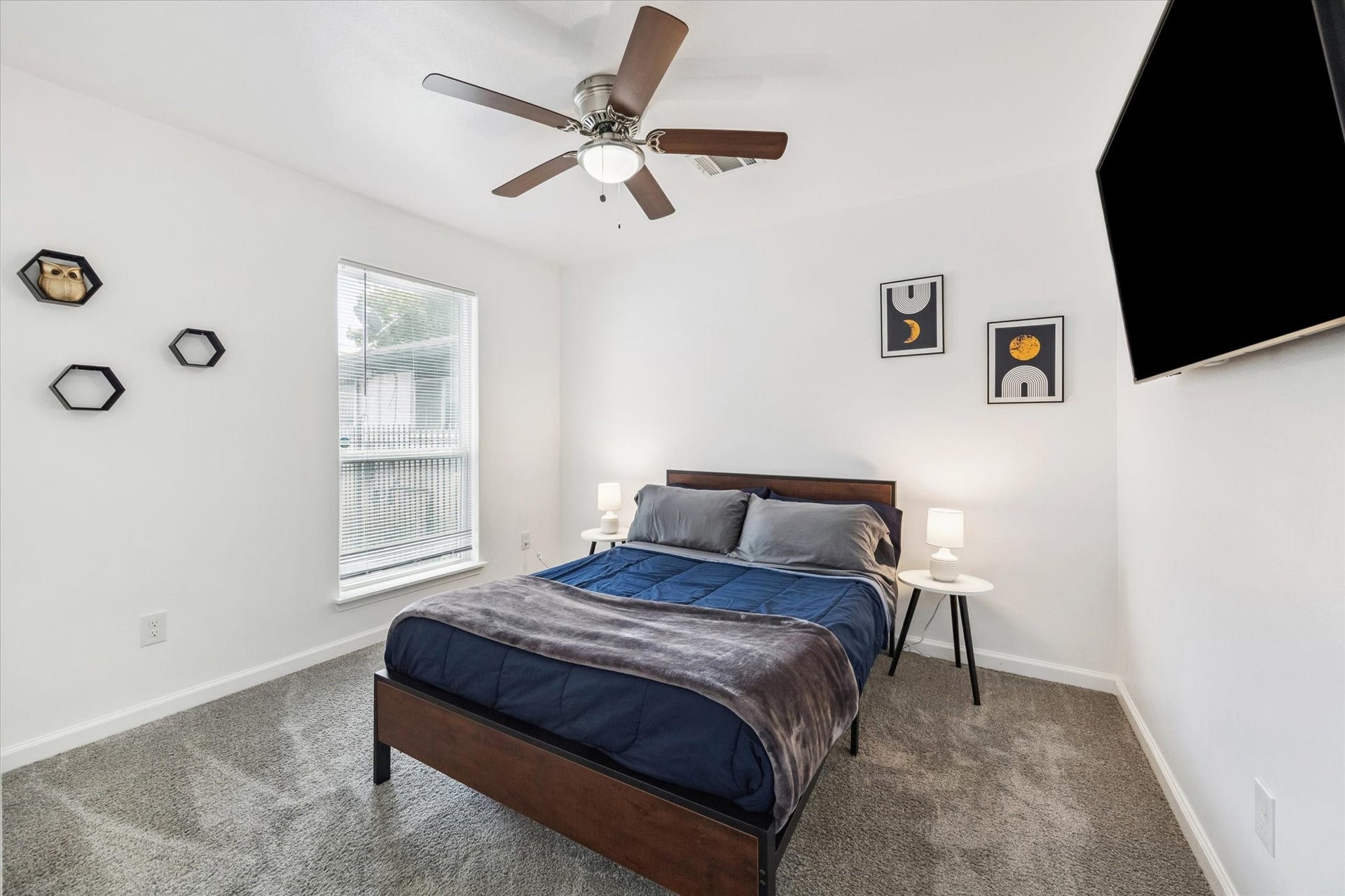 The first bedroom just off the hallway enjoys abundant natural light through large windows and includes a ceiling fan with a light kit for year-round comfort. Neutral tones and plush carpet create a cozy retreat ready for personalization.