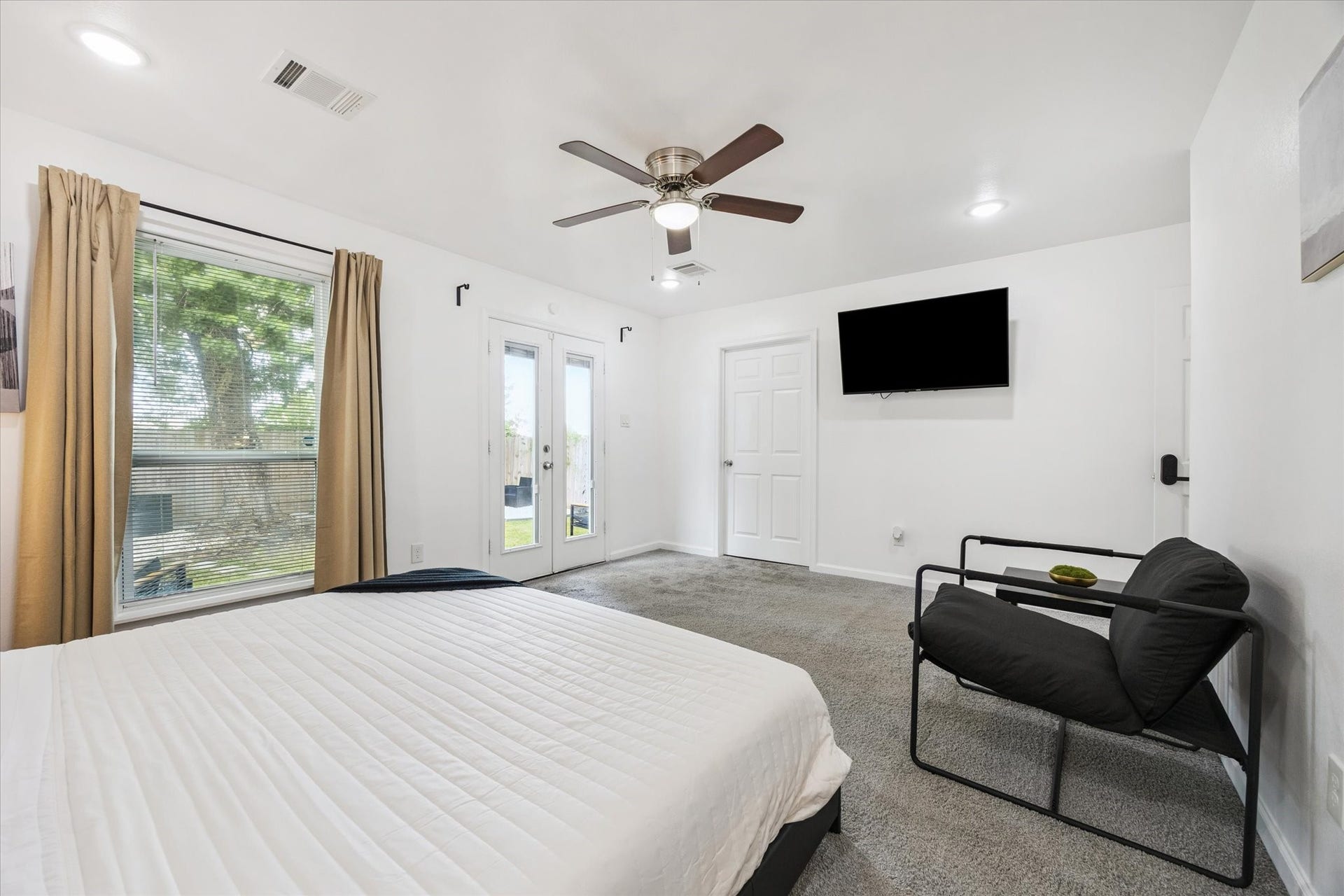 The spacious primary suite includes direct access to a large outdoor deck, recessed lighting, a ceiling fan with light kit, and its own ensuite bathroom. Natural light flows in through oversized windows and French doors, creating a relaxing retreat tucked away at the back of the home.