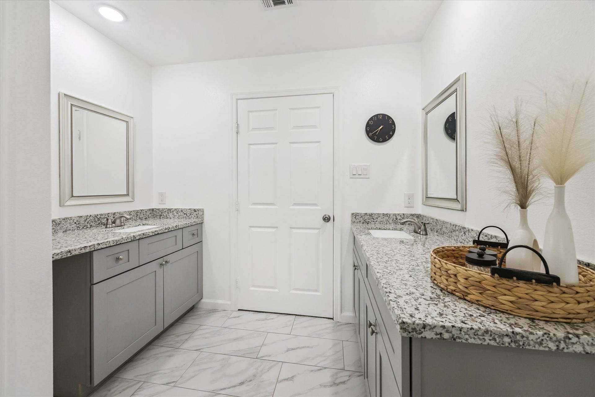The ensuite bath features two separate vanities with expansive granite countertops, undermount sinks, and framed mirrorsoffering ample space and privacy for busy mornings