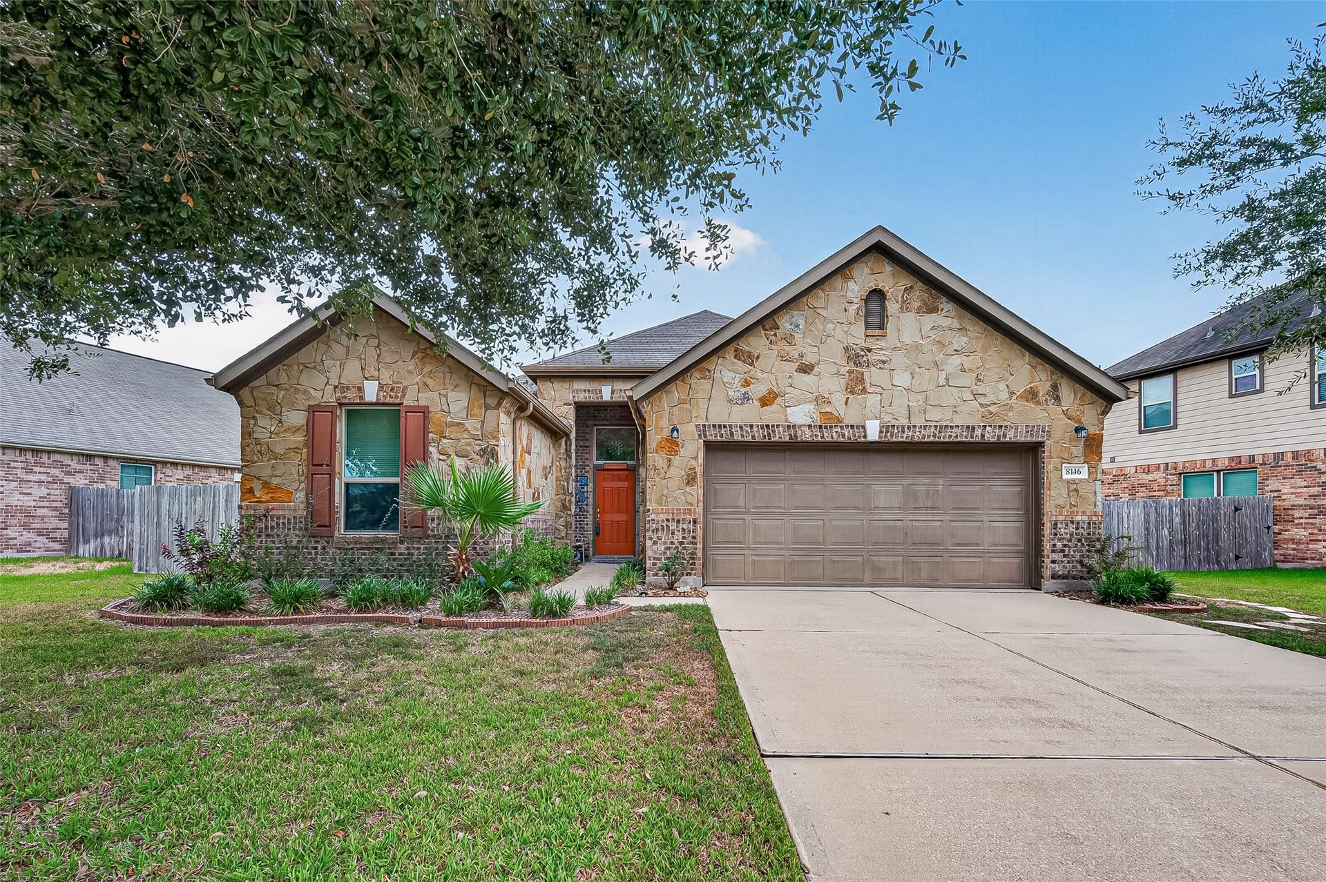 8146 Briscoe Foster Crossing, Richmond, TX 77406 Charming stone-accented home with a welcoming front entry, lush landscaping, and a spacious two-car garage.