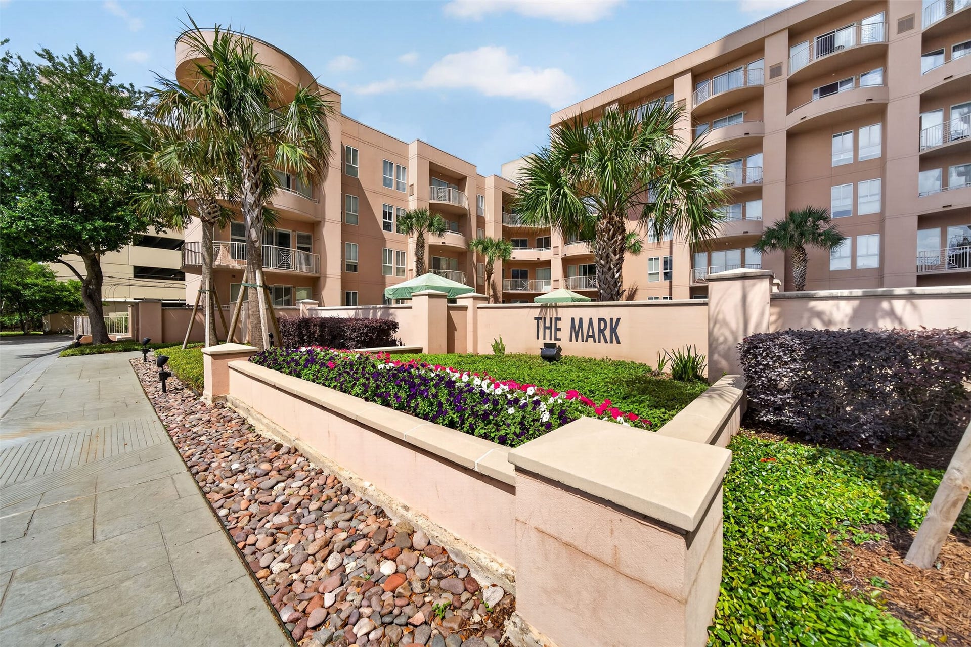 3505 Sage Road, #314, Houston, TX 77056 Modern condominium complex with 24 hour concierge, resort style pool and spa, fitness center, sauna, conference room and well-maintained landscaping, colorful flowerbeds, and inviting palm trees, offering a stylish and comfortable living environment.
