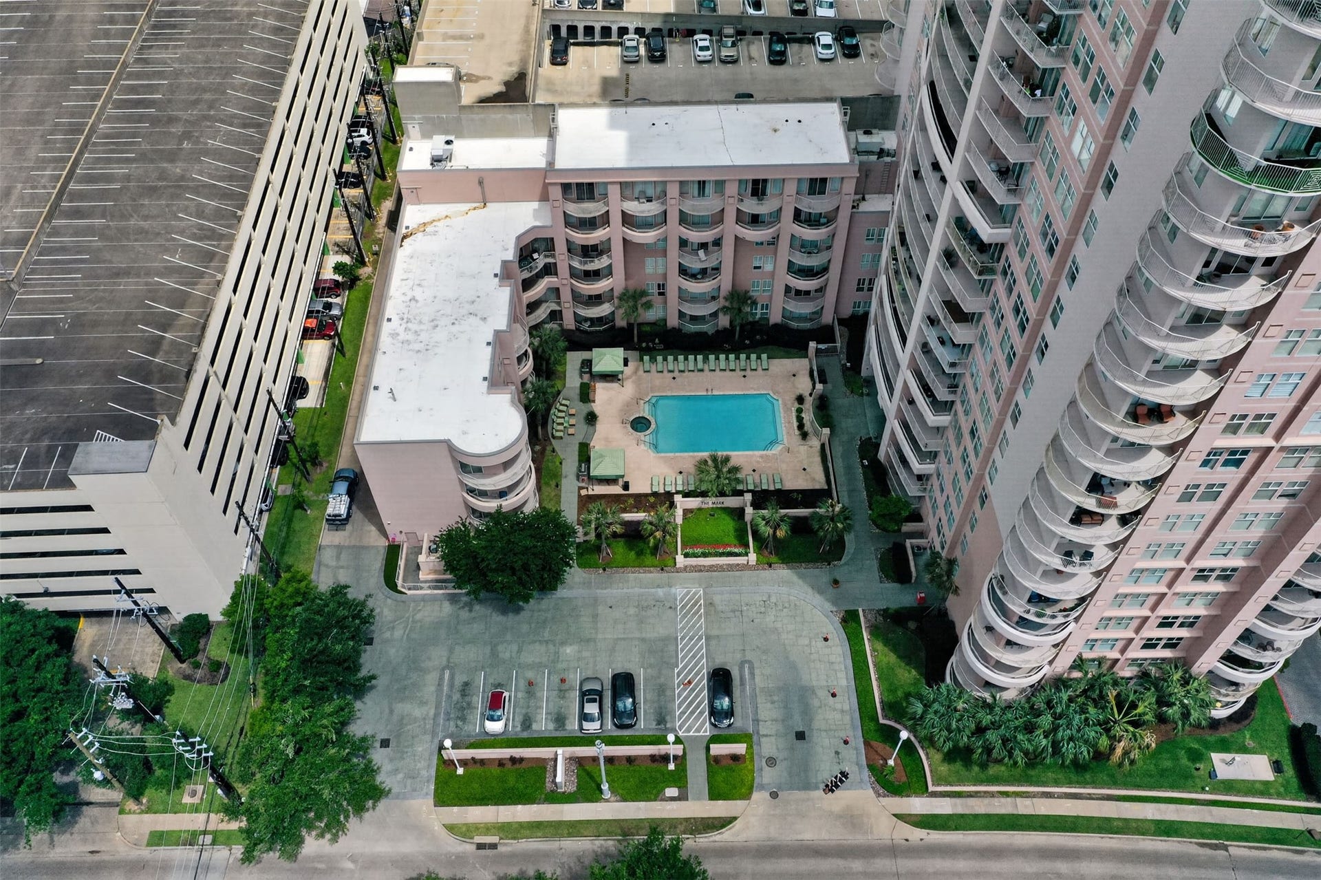 3505 Sage Road, #314, Houston, TX 77056 High-rise urban living with a central courtyard featuring a sparkling pool, surrounded by lush greenery and ample parking.