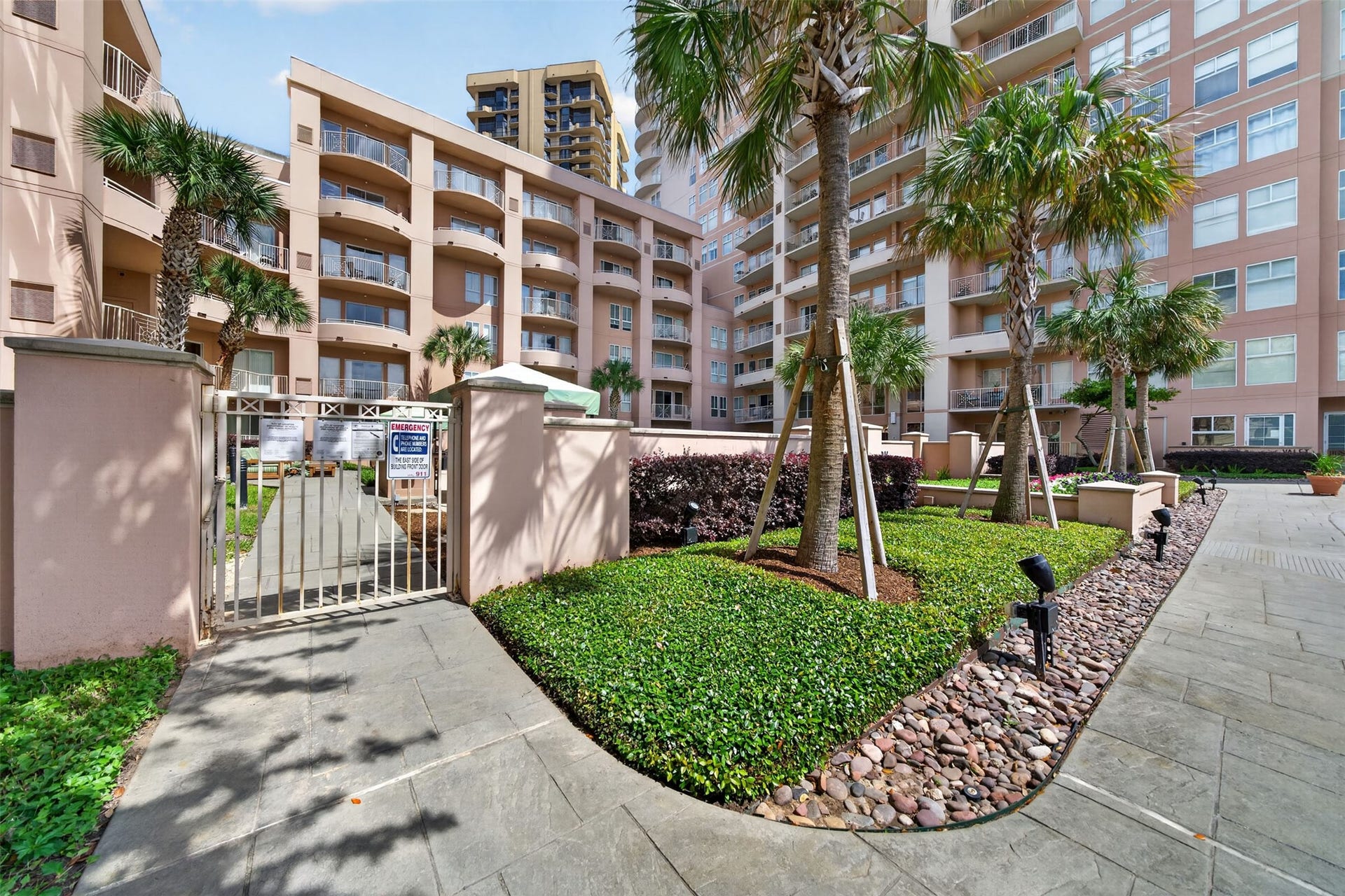 3505 Sage Road, #314, Houston, TX 77056 Modern condominium complex with lush landscaping, palm trees, and a secure gated entrance, offering a welcoming and stylish living environment.