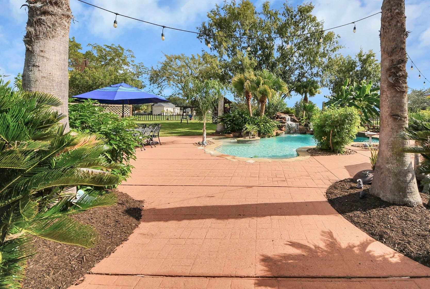 3903 Indian Point, Missouri City, TX 77459 The covered patio leads to the pool and entertainment area, with fenced yard and fishing lake with fountain beyond