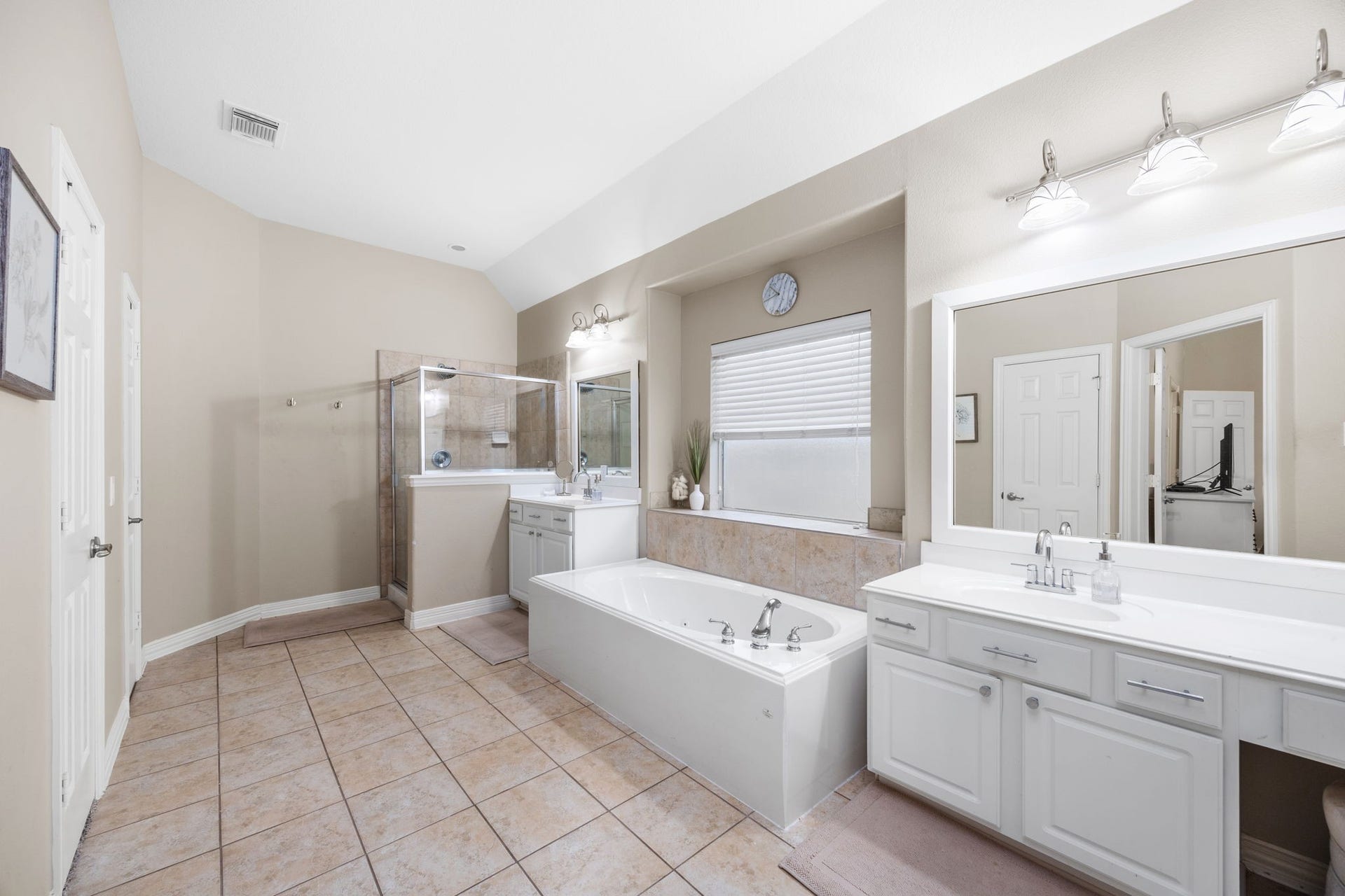 26823 Sandy Arbor Lane, Katy, TX 77494 Spacious primary bath offers separate vanity areas, a soaking tub beneath a large window and a separate glass-enclosed shower.