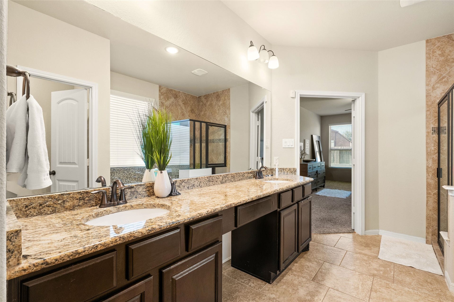 3650 Daintree Park Drive, Katy, TX 77494 Spacious bathroom featuring a double vanity with granite countertops, elegant lighting, and a walk-in shower with glass doors, seamlessly connected to the master bedroom.