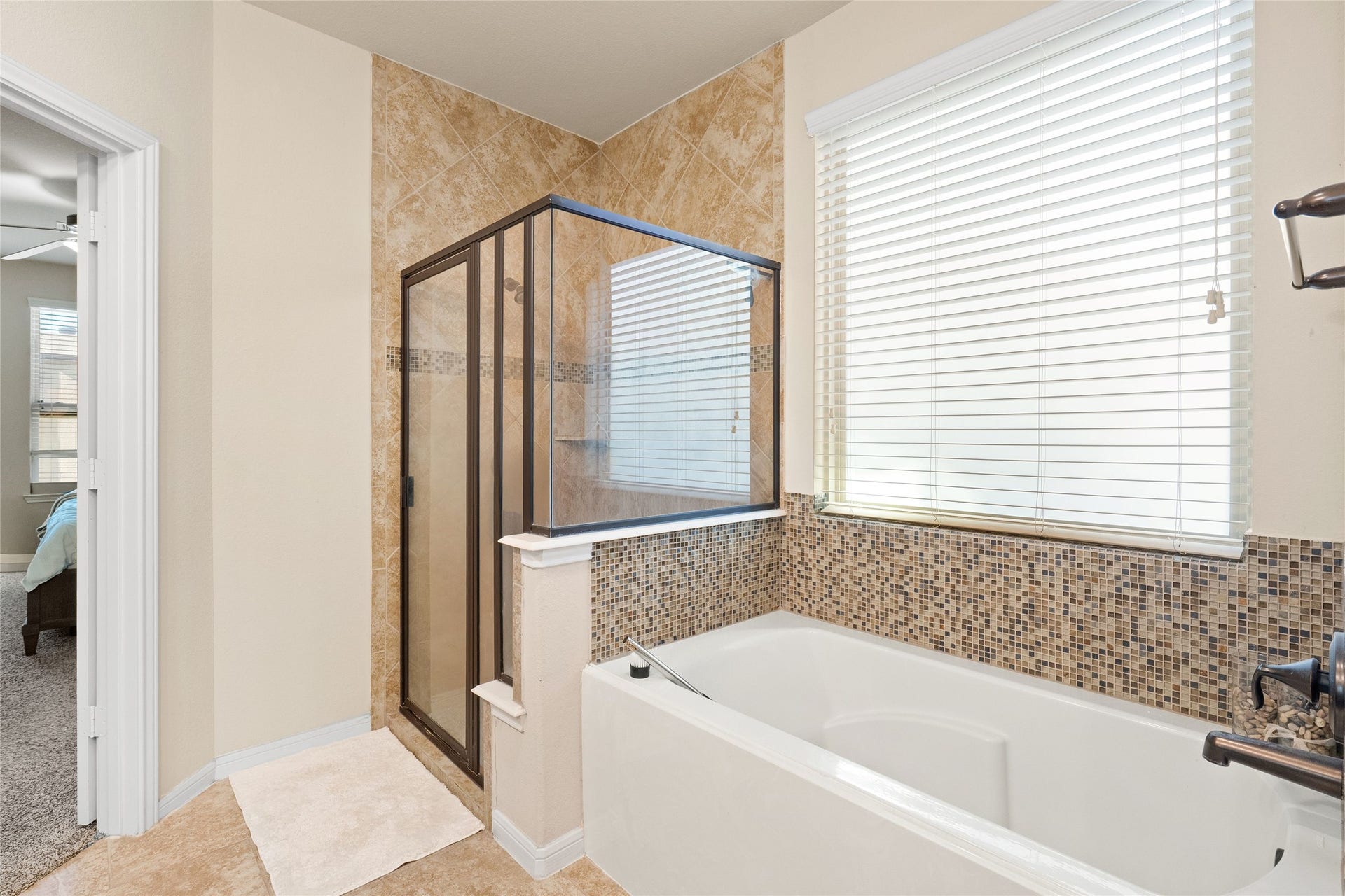 3650 Daintree Park Drive, Katy, TX 77494 Elegant bathroom featuring a luxurious soaking tub and a spacious glass-enclosed shower, complemented by stylish tile accents and abundant natural light.