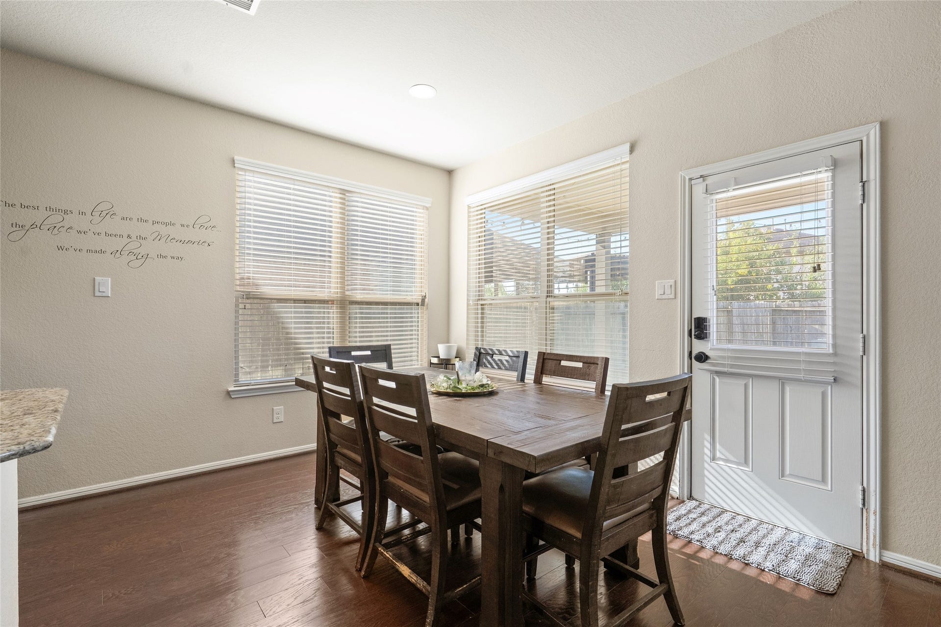 3650 Daintree Park Drive, Katy, TX 77494 Bright and welcoming dining area with ample natural light, featuring a spacious wooden table and easy access to the outdoor space through a door with charming window blinds.