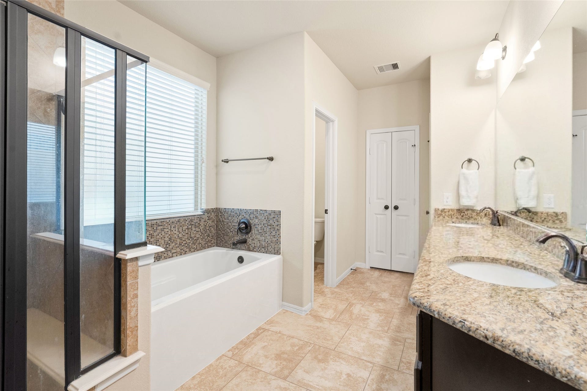 3650 Daintree Park Drive, Katy, TX 77494 Spacious bathroom with elegant granite countertops, dual sinks, a luxurious soaking tub, and a separate glass-enclosed shower.