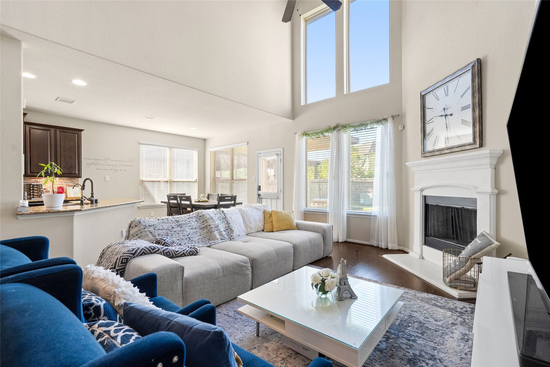 3650 Daintree Park Drive, Katy, TX 77494 Spacious living room featuring soaring ceilings, abundant natural light from large windows, and a cozy fireplace. The open floor plan flows seamlessly into the dining area and modern kitchen, perfect for entertaining.