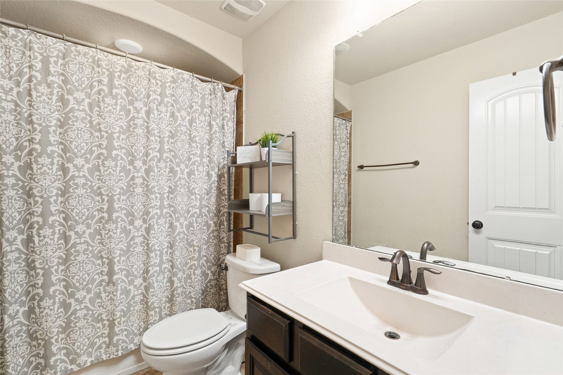 3650 Daintree Park Drive, Katy, TX 77494 Charming bathroom with elegant patterned shower curtain, sleek fixtures, and ample storage, offering a cozy and functional space.