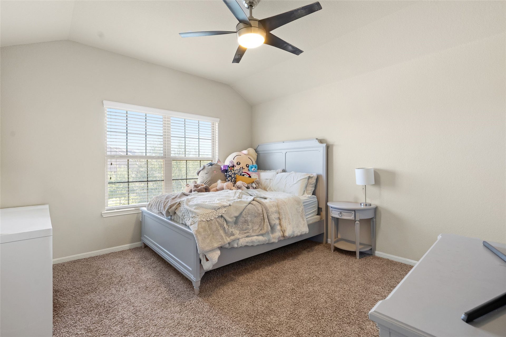 3650 Daintree Park Drive, Katy, TX 77494 Cozy bedroom with plush carpeting, featuring a large window that bathes the space in natural light, complemented by neutral walls and a modern ceiling fan.