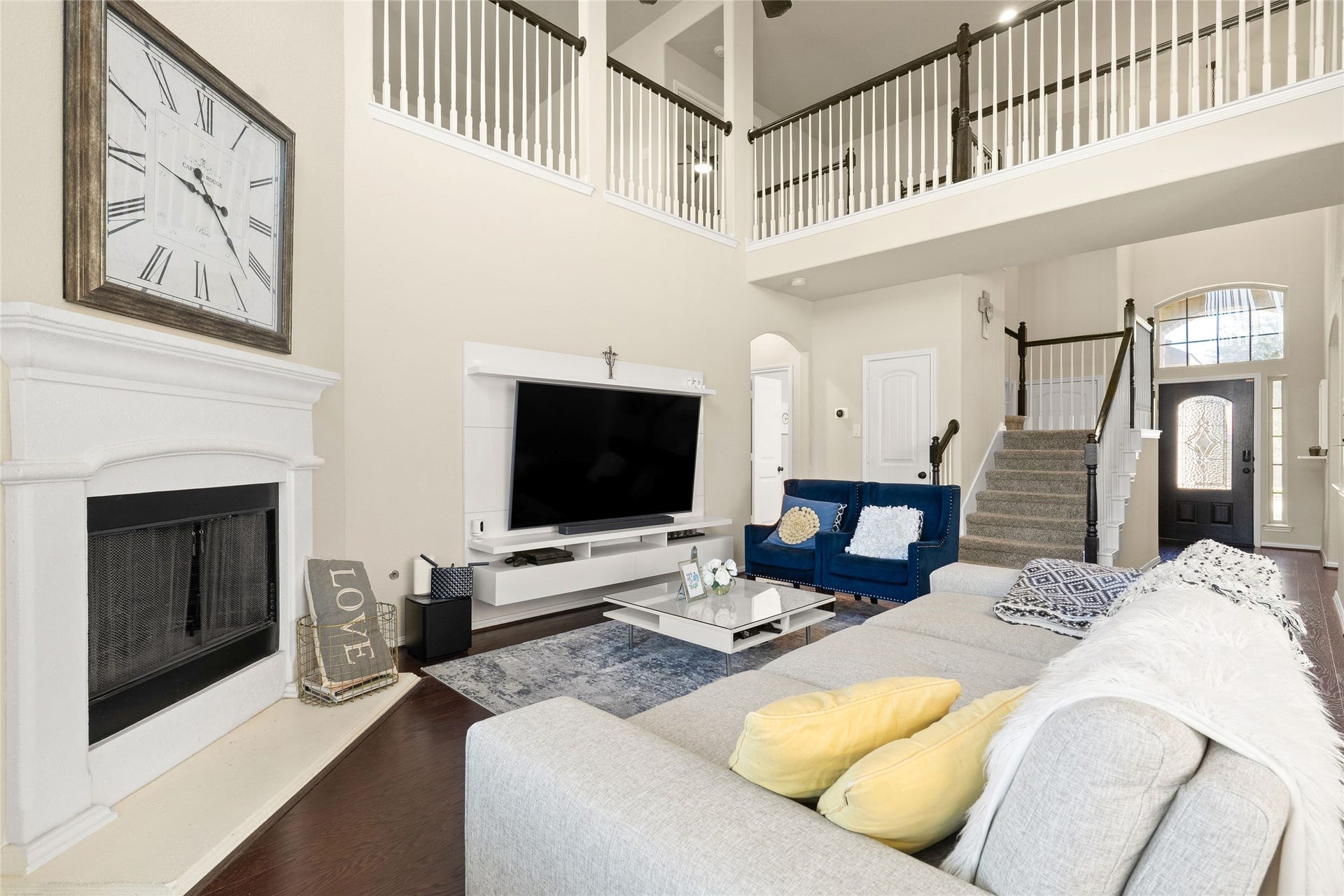3650 Daintree Park Drive, Katy, TX 77494 Elegant living room with high ceilings, featuring a cozy fireplace, modern entertainment center, and stylish seating. A grand staircase leads to the upper level, enhancing the open-concept design.