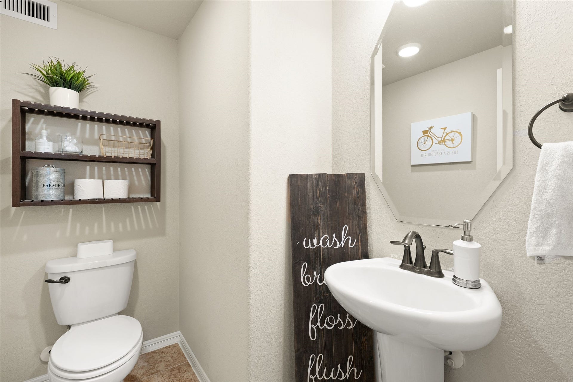 3650 Daintree Park Drive, Katy, TX 77494 Charming half-bathroom with a modern pedestal sink, elegant fixtures, and stylish shelving for storage.
