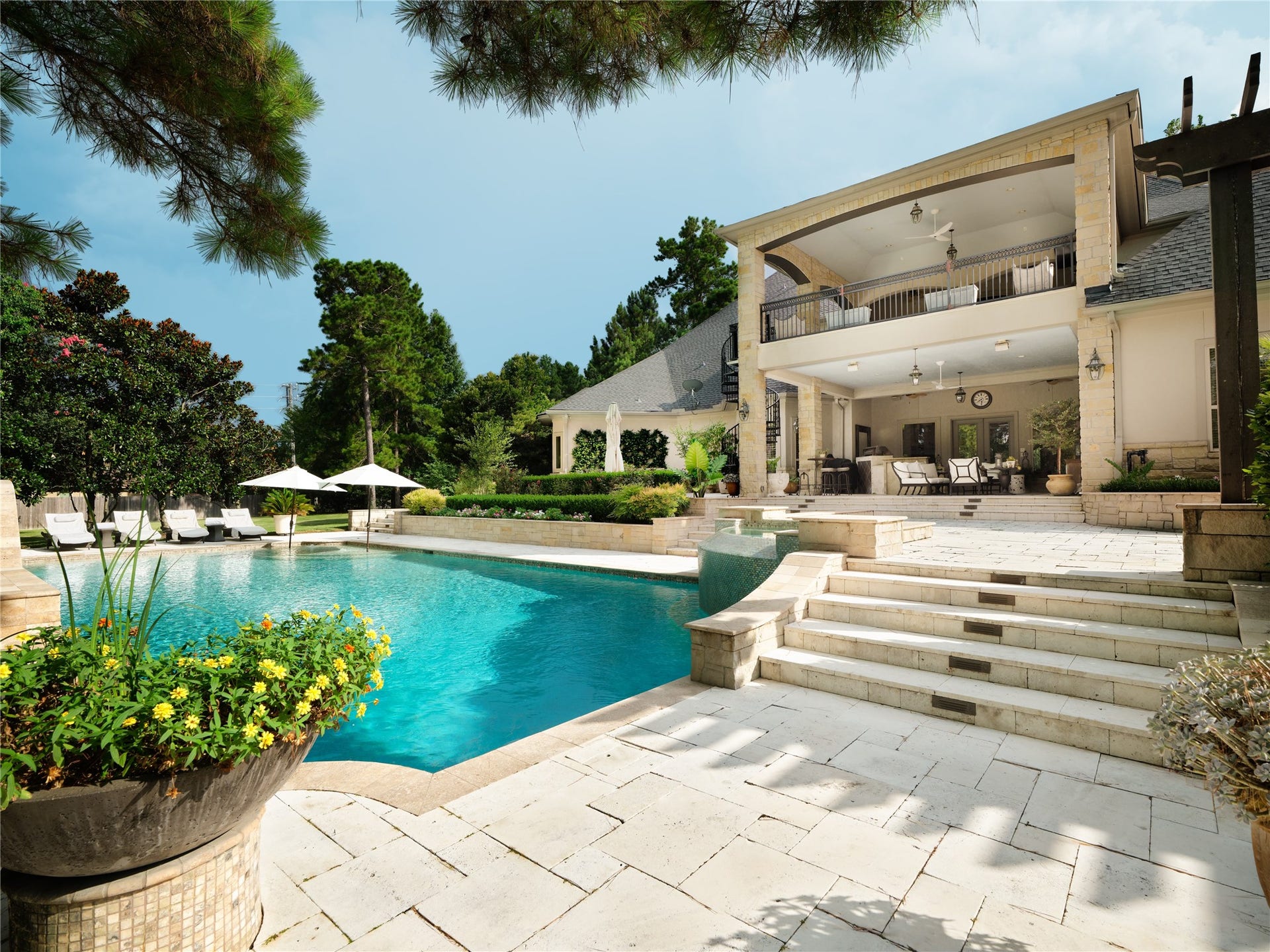 6702 Star Ledge Court, Spring, TX 77389 PRIVATE Grounds Beautifully designed for both grand entertaining and peaceful everyday living, the meticulously curated outdoor living environment unfolds across expansive limestone terraces surrounding a custom pool with elegant water features. Covered gathering spaces on both levels, lush landscaping, and multiple areas for lounging and dining create a seamless connection between the home and its surroundings. Gracefully composed to balance beauty, privacy, and functionality.
