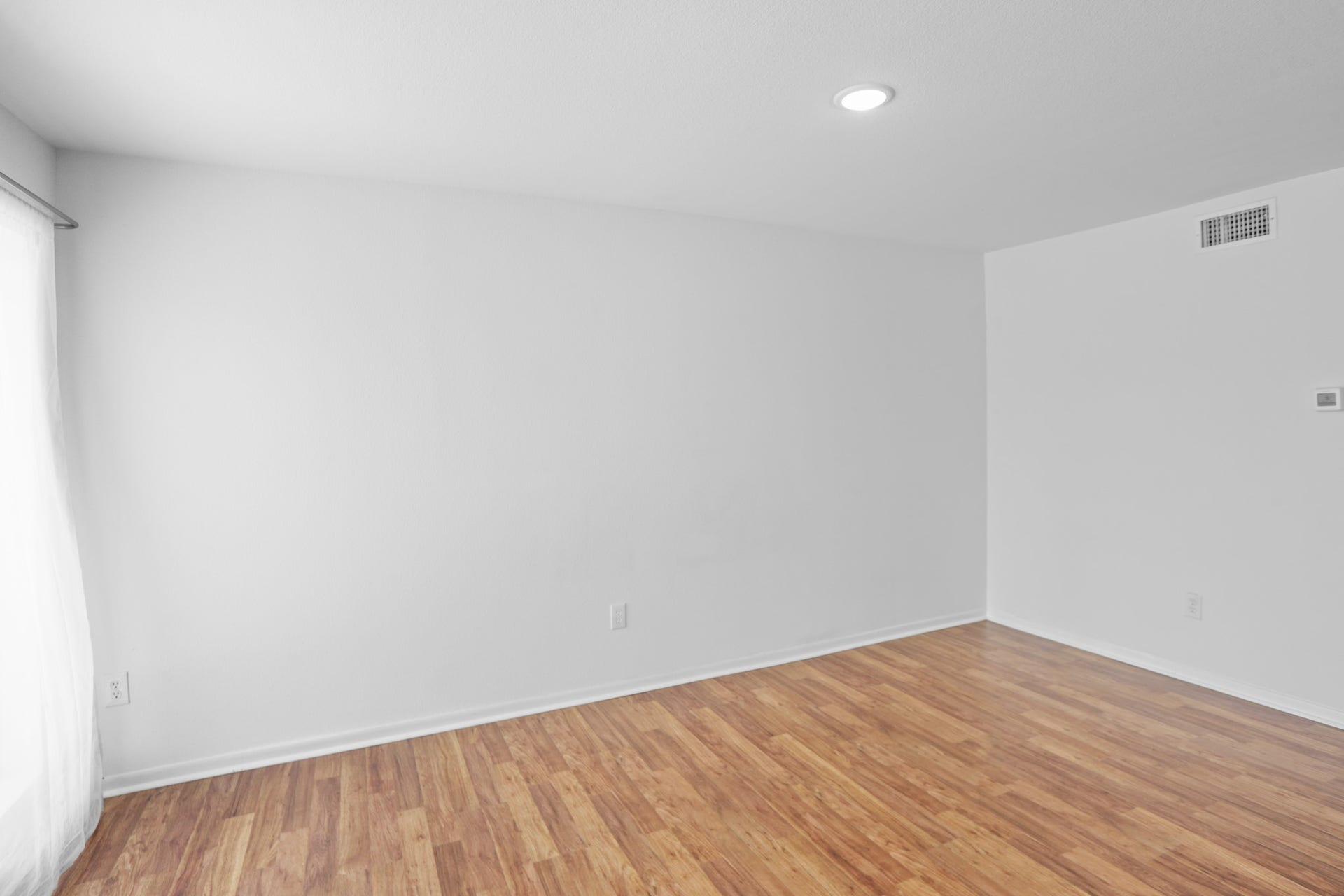 1408 Hughes Street, #11, Houston, TX 77023 Another view of the living space with large picture window. Notice the central A/C vent and digital thermostat.