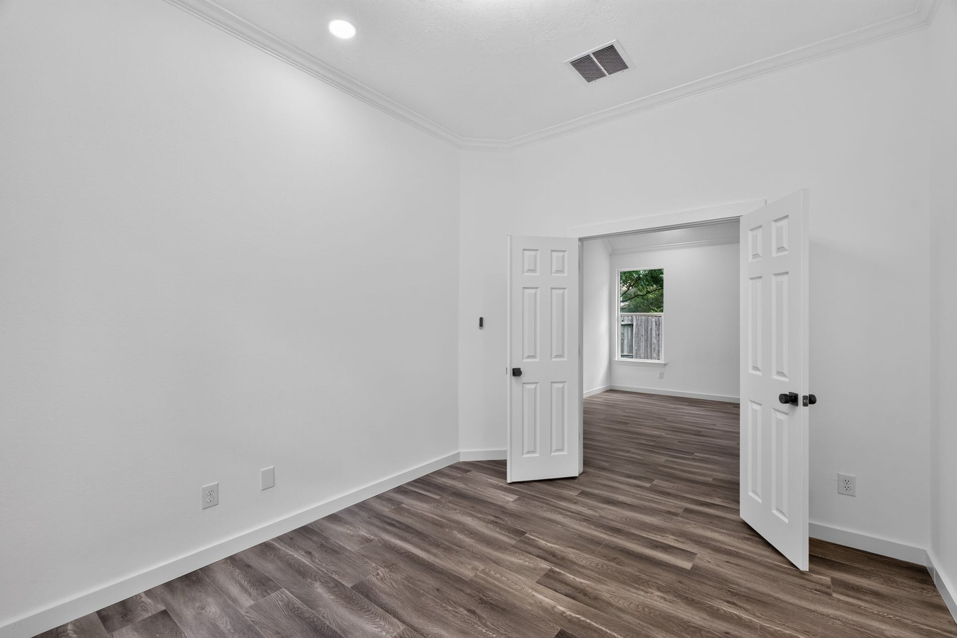 18 Griffin Hill Court, The Woodlands, TX 77382 A well-proportioned secondary bedroom at 18 Griffin Hill Court offers clean white walls, dark hardwood-style flooring, and easy access to the hallway beyond. This comfortable room provides flexibility for use as a guest room, children's bedroom, or home office ready to be personalized to perfectly suit your unique lifestyle and needs.