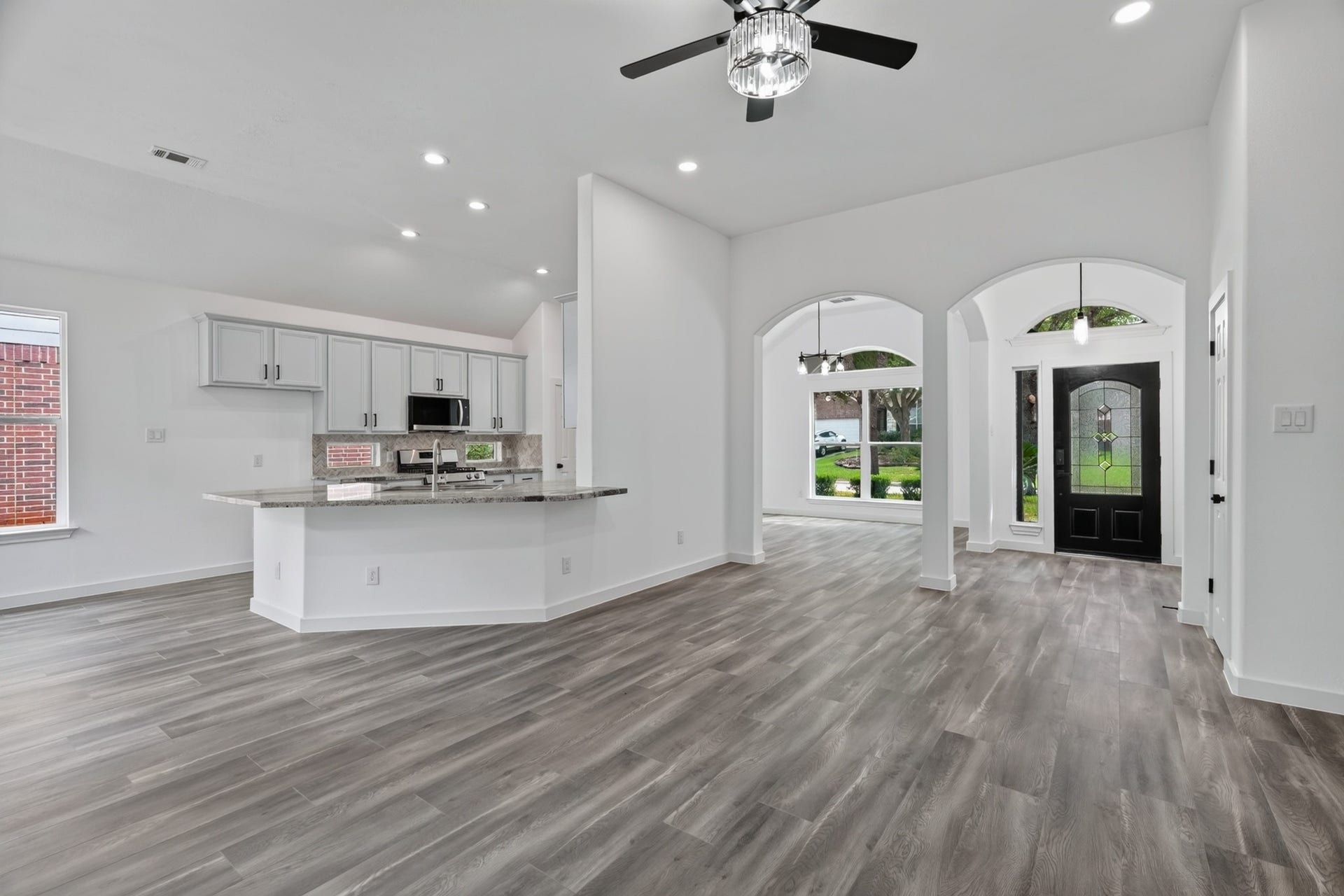 18 Griffin Hill Court, The Woodlands, TX 77382 A seamless open-concept design connects the gourmet kitchen to the main living areas at 18 Griffin Hill Court. This perspective from the kitchen shows the expansive living space beyond, demonstrating how this home's layout perfectly supports an active family lifestyle while keeping the chef connected to the action. Dark hardwood-style floors tie everything together.