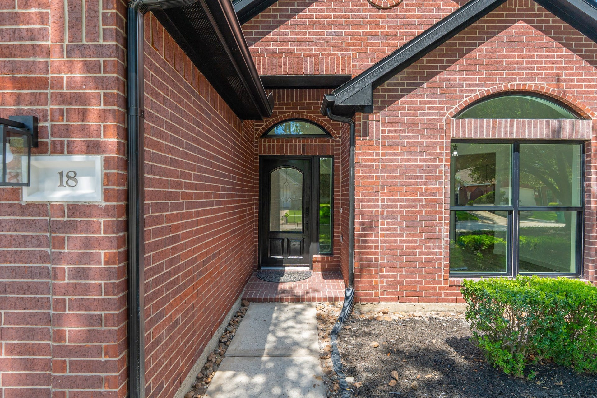 18 Griffin Hill Court, The Woodlands, TX 77382 Step into elegance at the arched brick entry of 18 Griffin Hill Court. This beautifully detailed front entrance features warm red brick surrounds, a striking arched transom window above the door, and tasteful exterior lighting setting the tone for the quality craftsmanship and attention to detail found throughout this exceptional home.