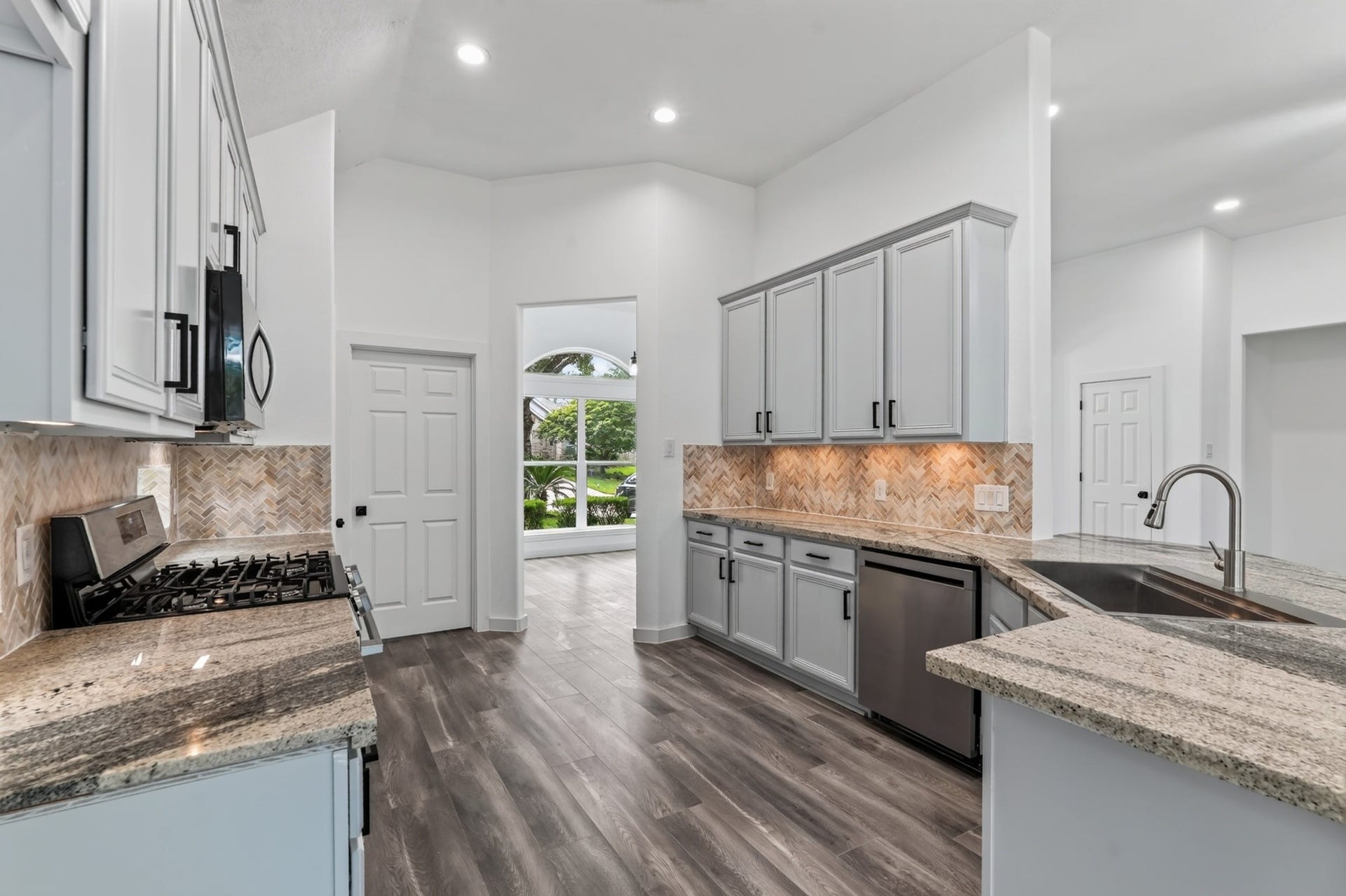 18 Griffin Hill Court, The Woodlands, TX 77382 Premium stainless steel appliances and beautiful teal backsplash tiles take center stage in this kitchen view at 18 Griffin Hill Court. A range with stainless hood, refrigerator, and dishwasher are thoughtfully integrated into the cabinetry, combining impeccable style and high performance for a truly chef-worthy cooking and entertaining experience.