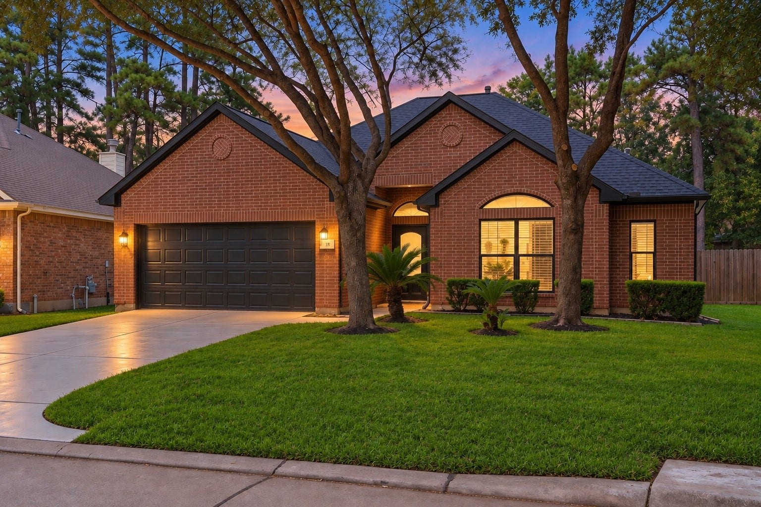 18 Griffin Hill Court, The Woodlands, TX 77382 Another breathtaking twilight view of 18 Griffin Hill Court's classic brick facade. The deep purple and pink dusk sky creates a dramatic and romantic backdrop, while warm interior lighting glows invitingly through the windows. Mature trees frame this stunning single-story home in a picturesque evening scene. (PHOTO MAY BE AI ENHANCED.)