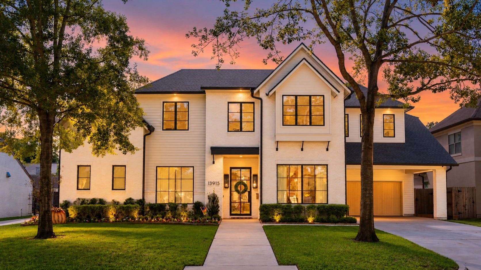 13915 Queensbury Lane, Houston, TX 77079 An impressive sight at sunset! This modern farmhouse comes to life with warm exterior lighting, beautifully illuminated landscaping, and inviting interior light glowing through expansive windows. The striking architectural details and mature trees create a picture-perfect setting that showcases the home's timeless curb appeal.
