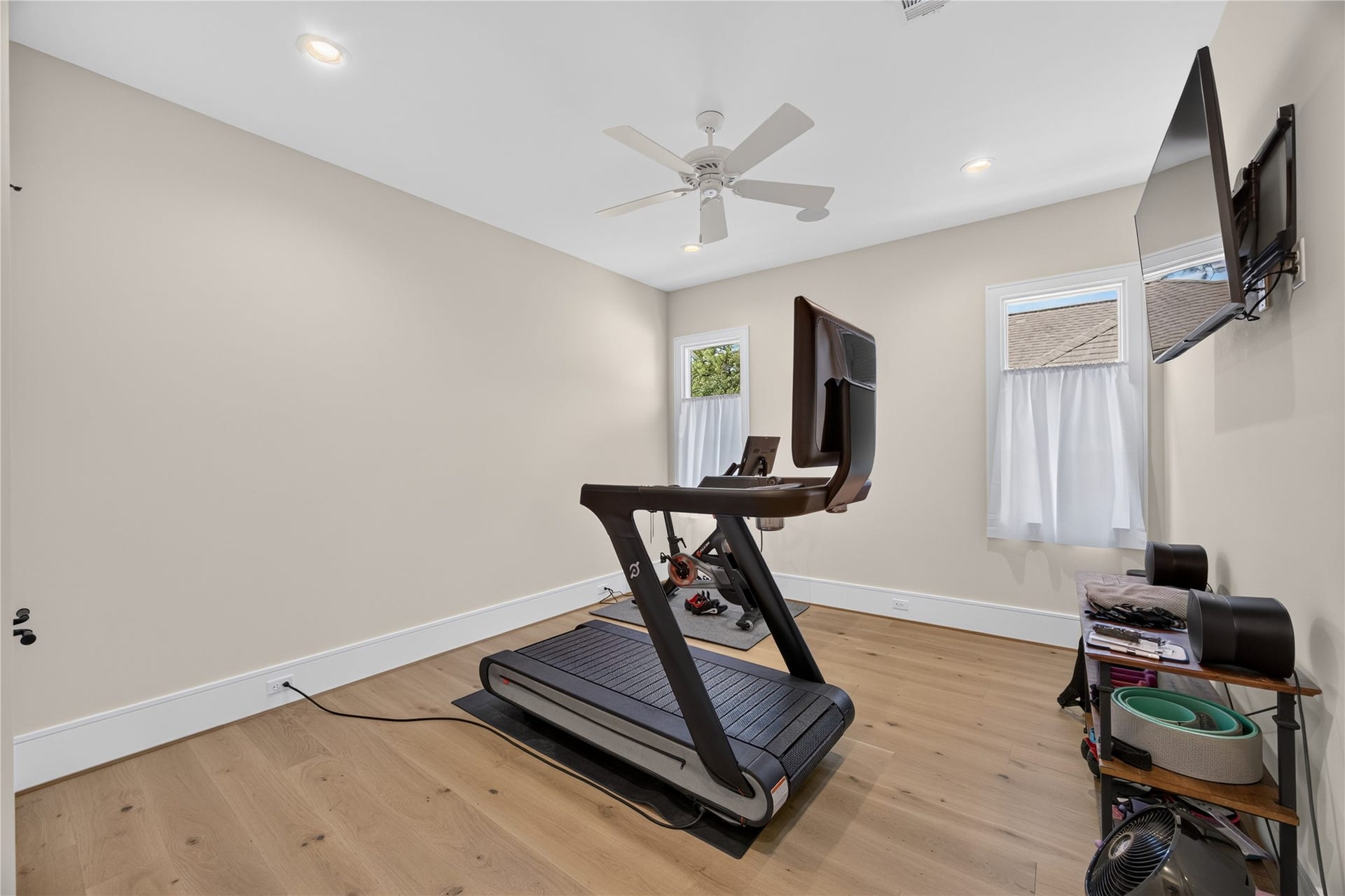 13915 Queensbury Lane, Houston, TX 77079 Versatile upstairs room currently used as a home gym, featuring wide-plank wood flooring, recessed lighting, a ceiling fan, and two windows providing natural light. The spacious layout offers flexibility for a fitness studio, additional bedroom, home office, or multipurpose room.