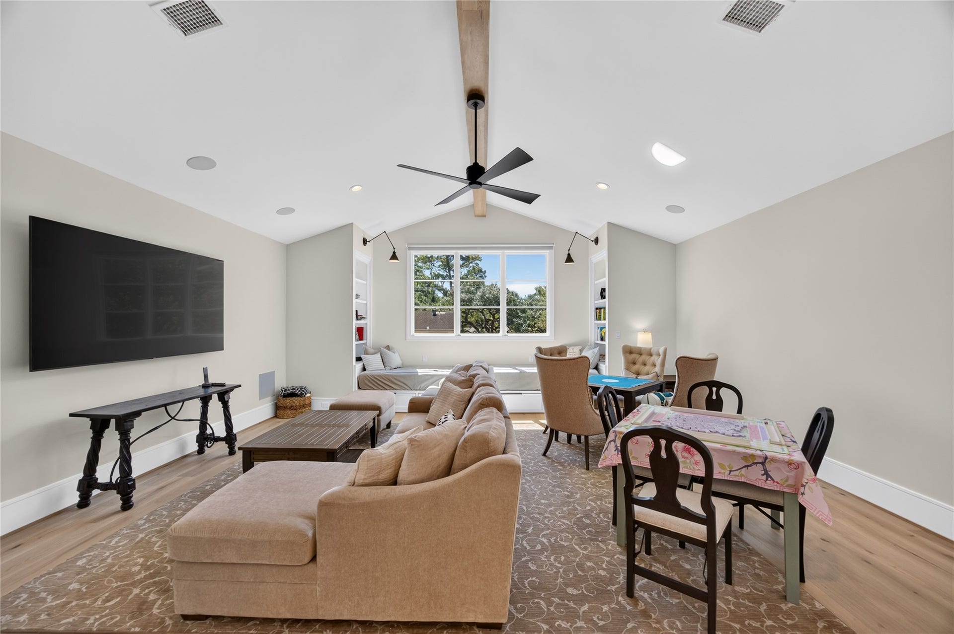 13915 Queensbury Lane, Houston, TX 77079 The upstairs game room offers an inviting retreat with a vaulted ceiling, exposed wood beam, and beautiful natural light. A cozy window seat framed by built-in shelving adds charm, while the open layout provides flexibility for movie nights, entertaining, or simply relaxing.