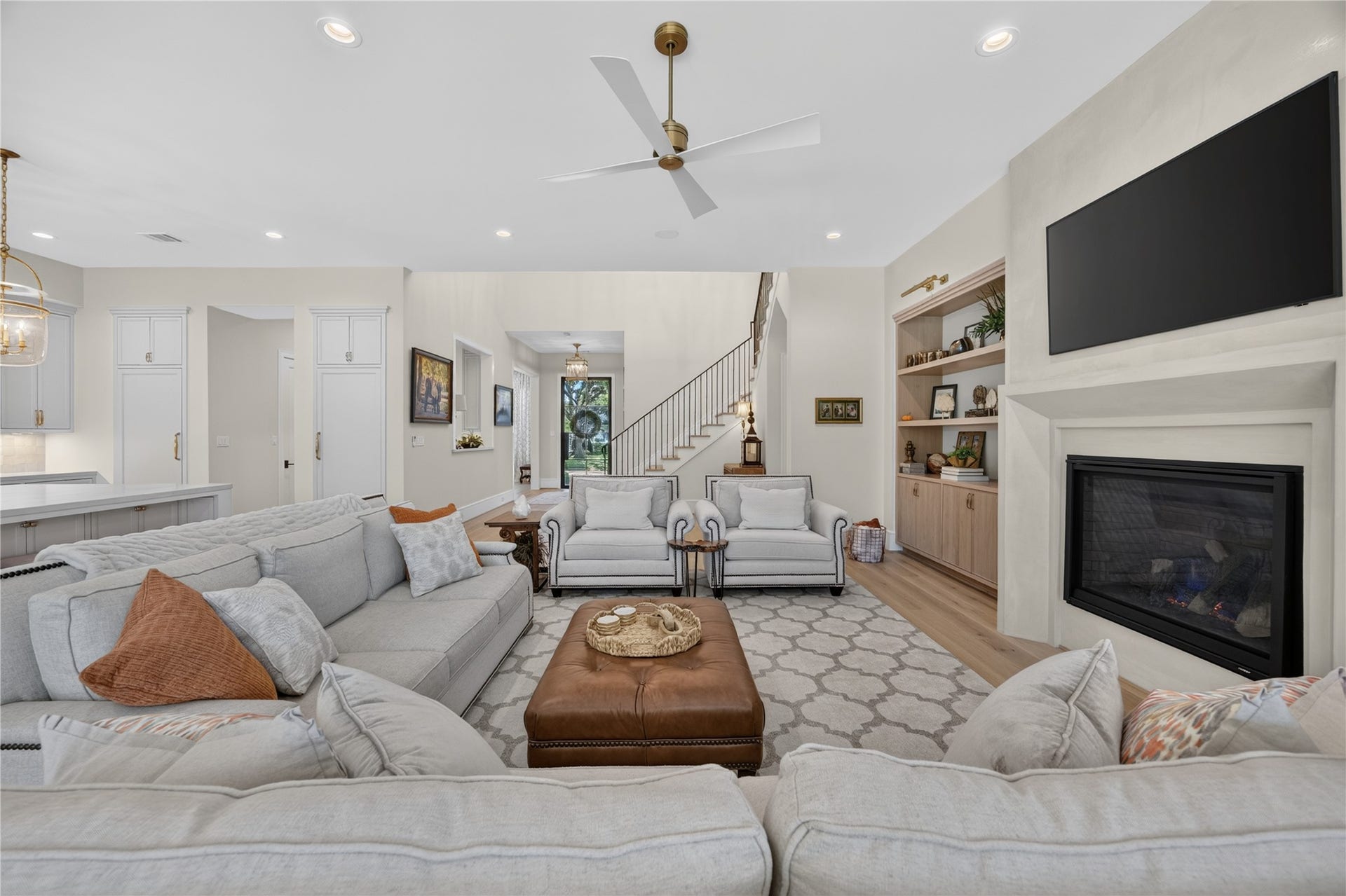 13915 Queensbury Lane, Houston, TX 77079 An alternate view showcases the spacious open-concept living area, highlighted by a decorative mock fireplace, custom built-ins, recessed lighting, and elegant ceiling fan. The thoughtful layout flows effortlessly into the kitchen while offering plenty of room for comfortable seating and gatherings.