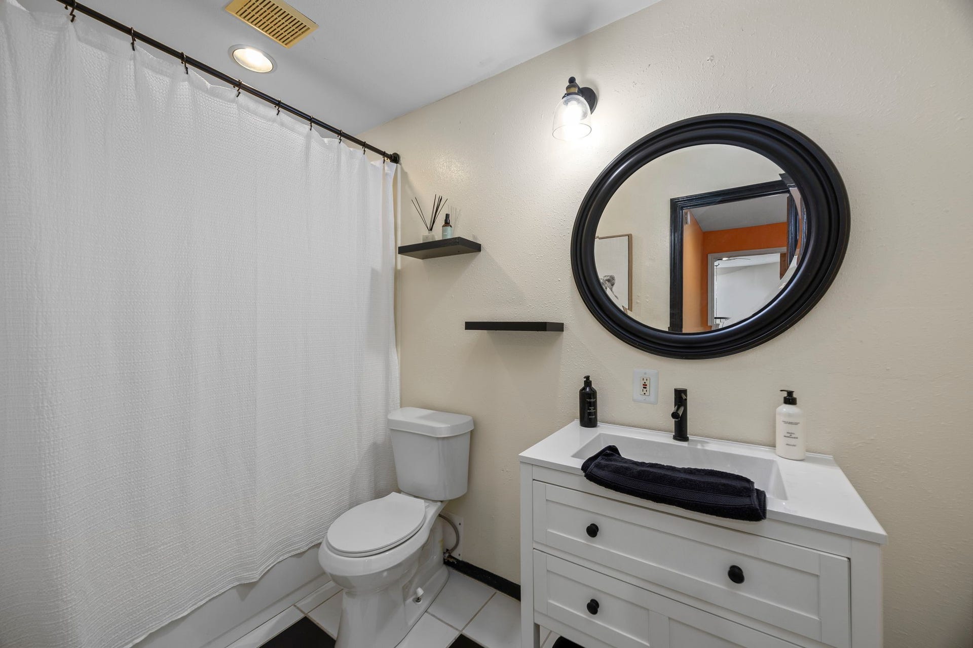 1622 Rambling Stone Drive, Richmond, TX 77406 Private bathroom features a white vanity with storage, decorative round mirror, and tub/shower combination, completing this versatile upstairs suite.