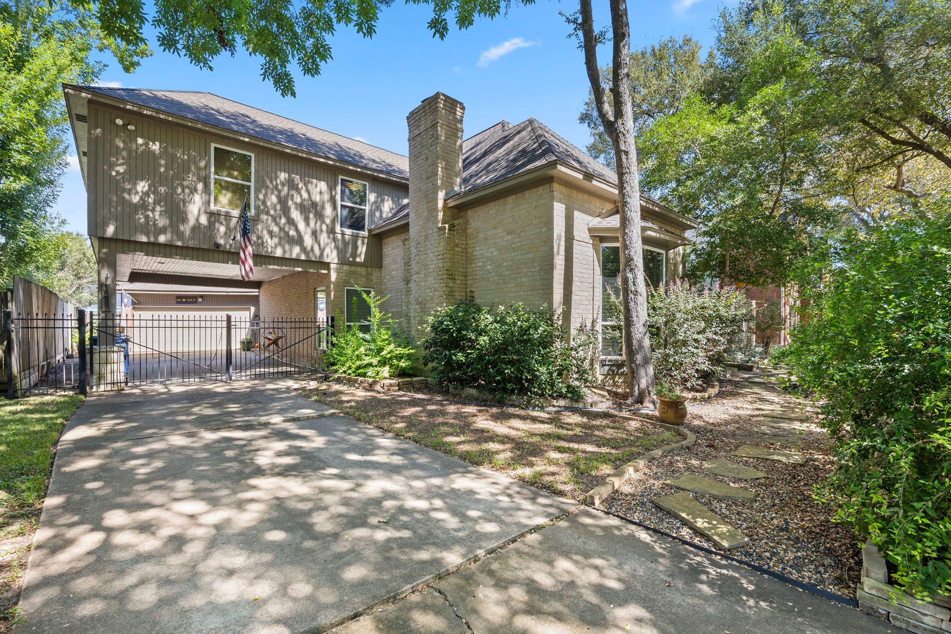 1622 Rambling Stone Drive, Richmond, TX 77406 An extended driveway leads to a portce cochere and detached garage, while mature trees, established landscaping, and a combination of brick and siding add to the home's distinctive exterior character.