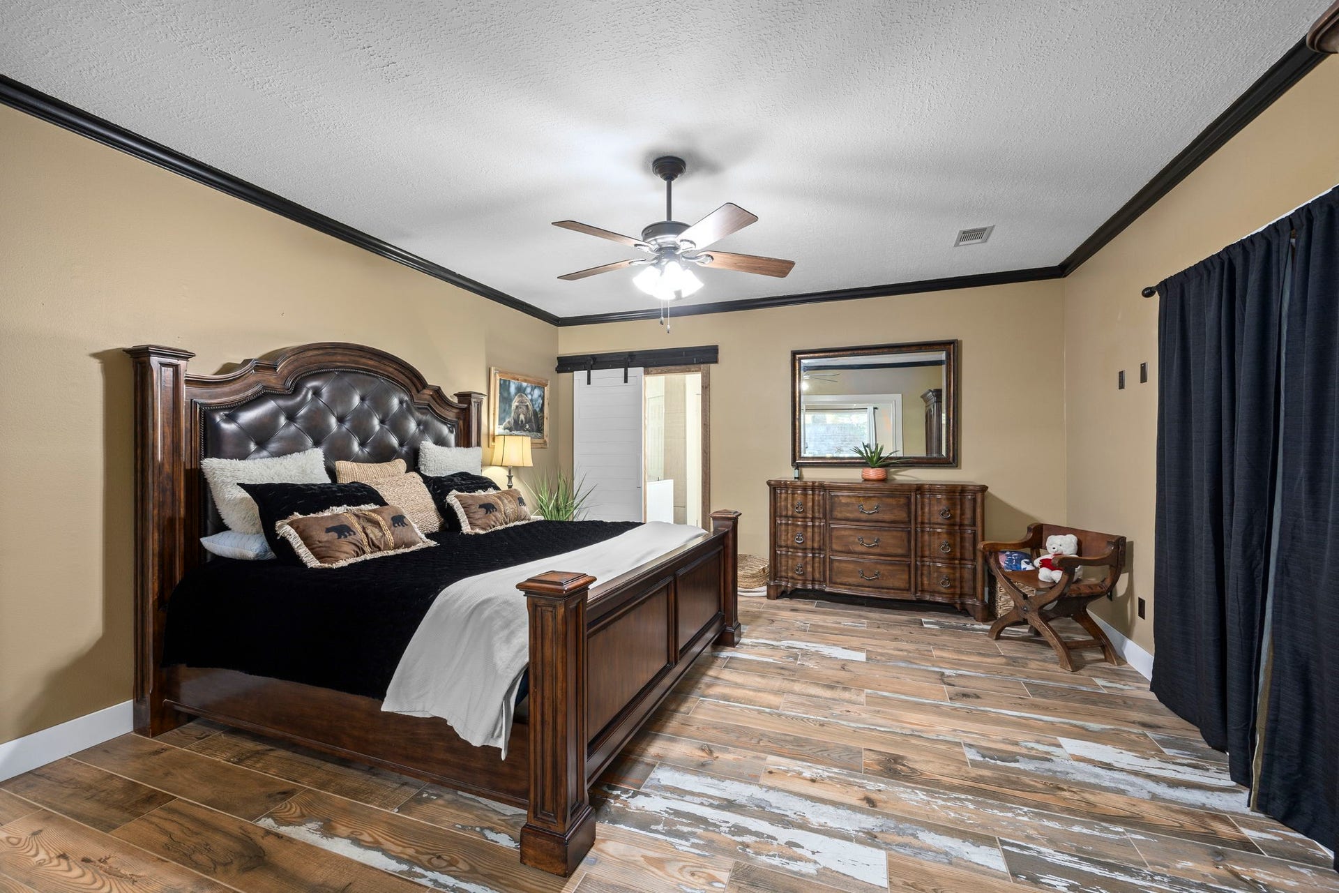 1622 Rambling Stone Drive, Richmond, TX 77406 The spacious primary bedroom offers a comfortable retreat with a tray ceiling, wood-look flooring, and plenty of room for substantial furnishings. A neutral color palette and contrasting dark trim add definition to the space.
