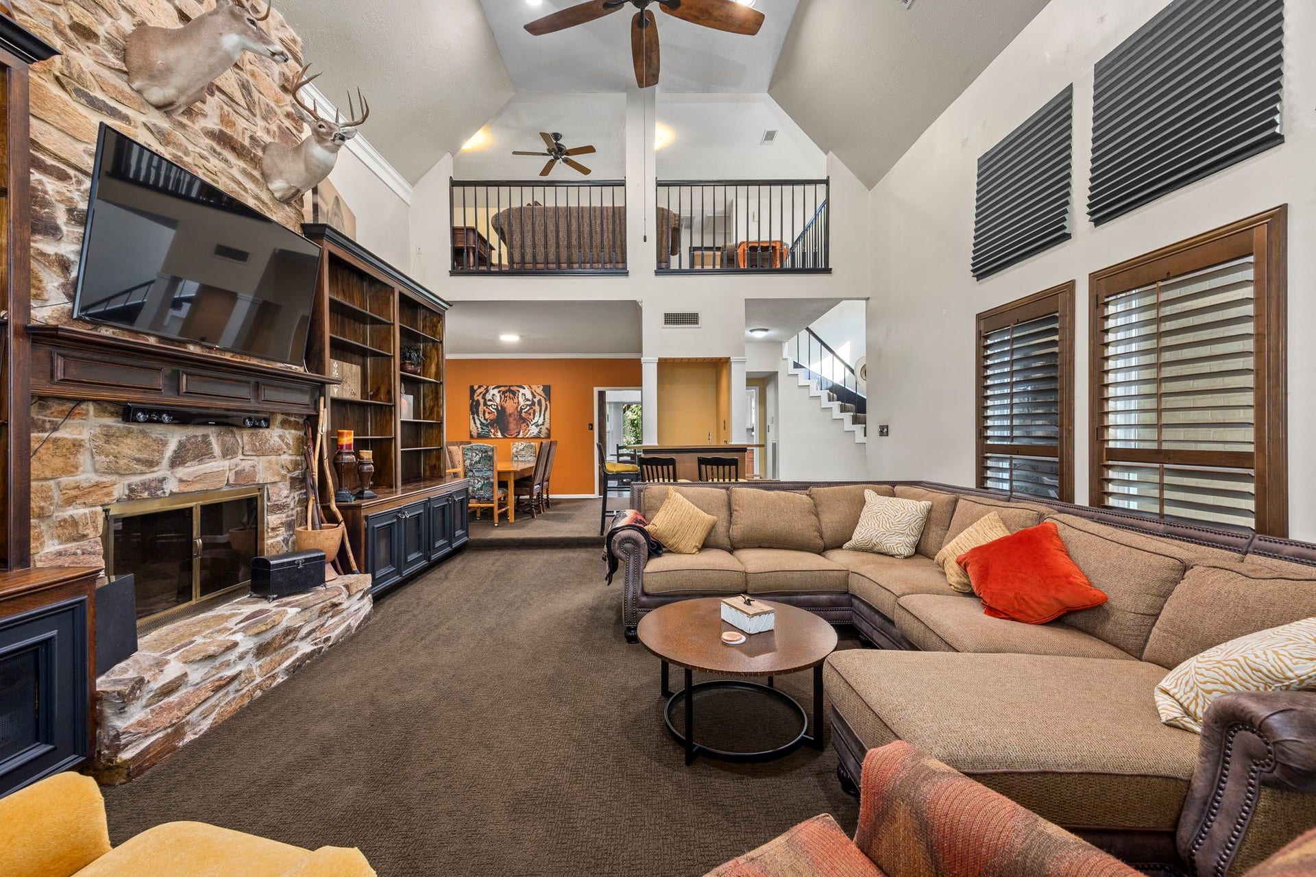 1622 Rambling Stone Drive, Richmond, TX 77406 The dramatic two-story living room is anchored by a floor-to-ceiling stone fireplace flanked by extensive built-in cabinetry. Vaulted ceilings, an open upstairs balcony, and generous seating space create an impressive setting for gathering and entertaining.