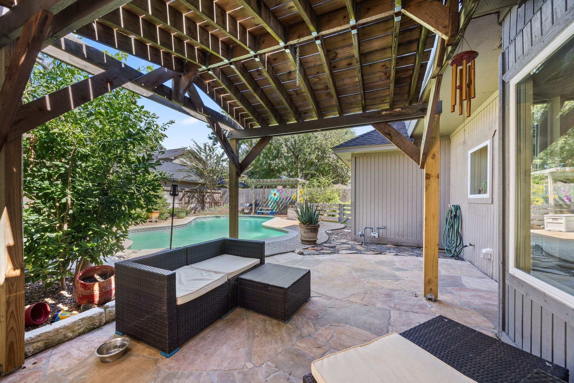1622 Rambling Stone Drive, Richmond, TX 77406 Spacious covered patio with wood-beamed structure offers a shaded retreat for outdoor seating, dining, and entertaining. Conveniently located alongside the pool, it provides an inviting space to relax and enjoy the backyard.