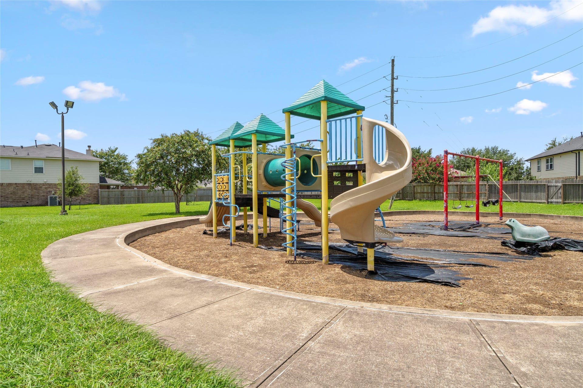 9423 Mineral Rock Lane, Richmond, TX 77407 Discover endless family fun in this vibrant play park, featuring a modern playground set amidst lush green surroundings, perfect for children to explore and enjoy.