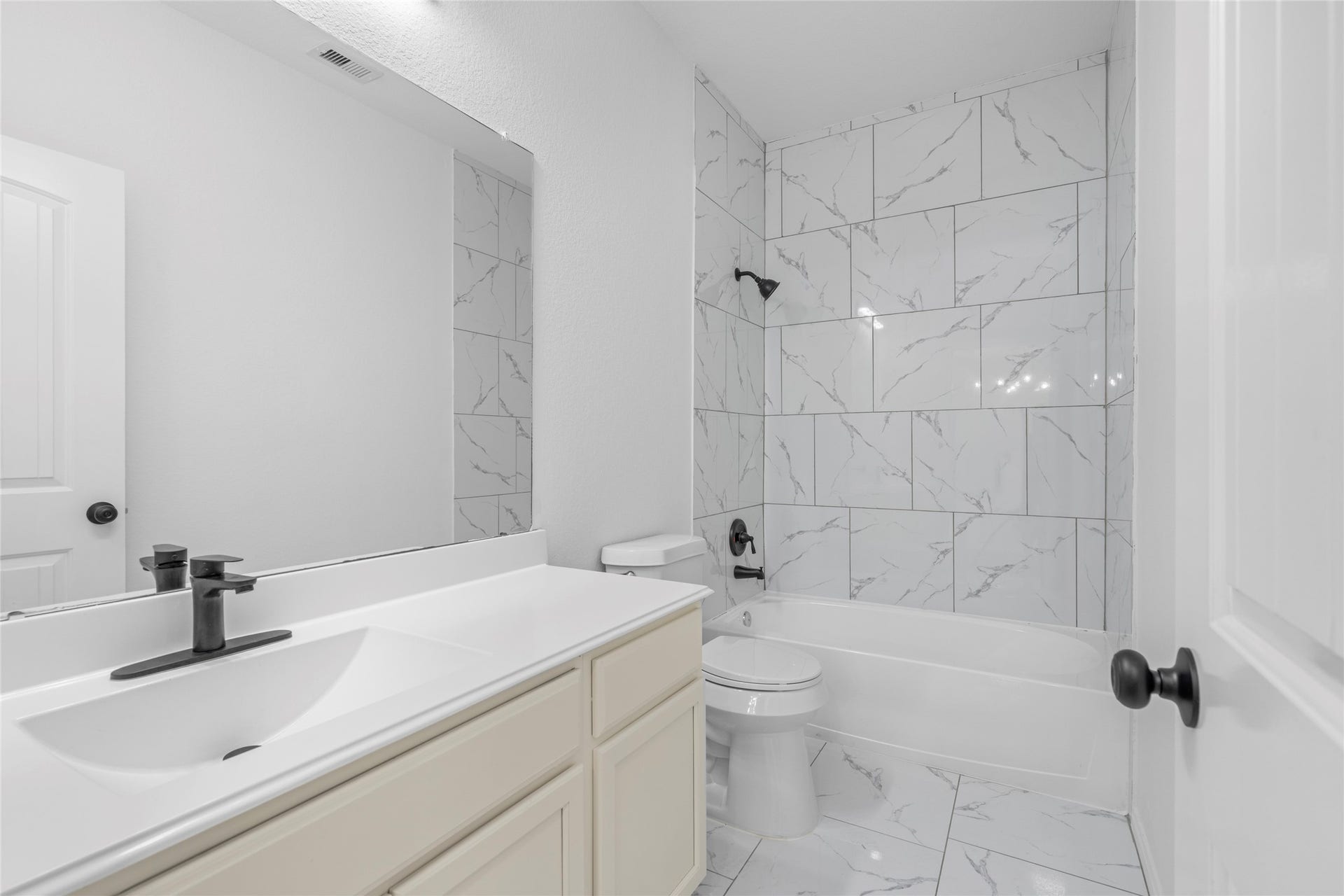 9423 Mineral Rock Lane, Richmond, TX 77407 Experience modern elegance in this bathroom featuring a sleek tub/shower combo set against stylish patterned tiles, complemented by a chic vanity and contemporary fixtures.
