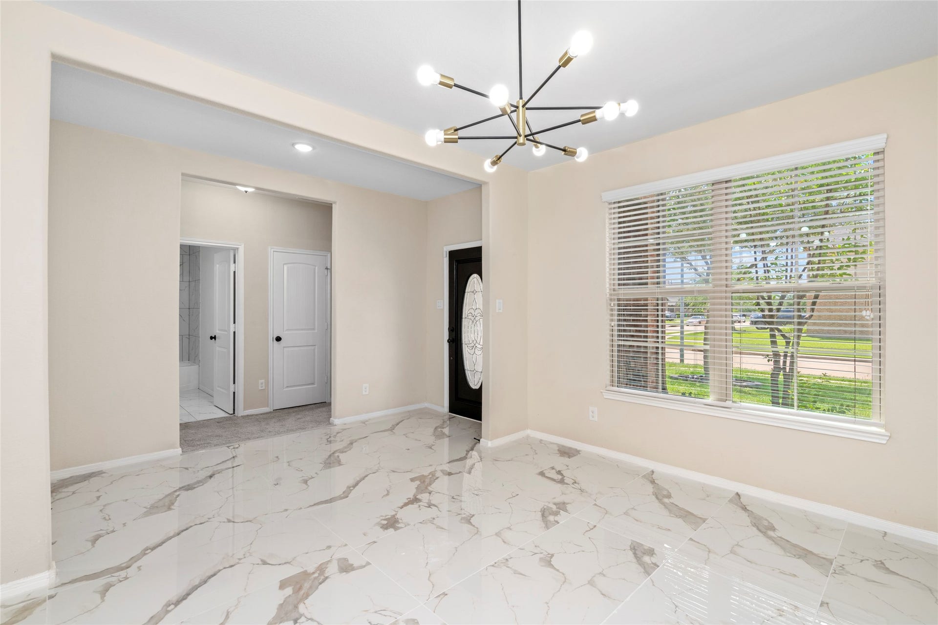 9423 Mineral Rock Lane, Richmond, TX 77407 Elegant dining space flows seamlessly into a welcoming entryway and the privacy of bedroom 1, enhanced by sleek tile flooring and abundant natural light.